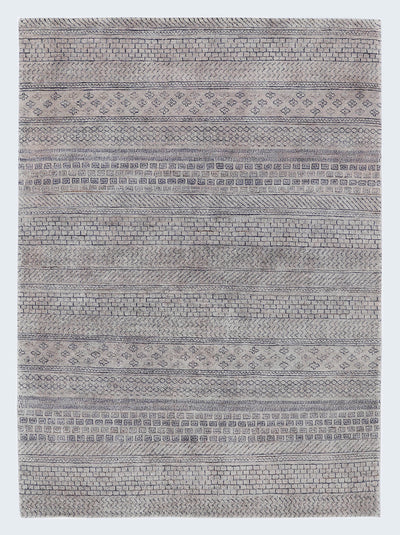 A full view of a plush, hand-knotted Gabbeh rug from the Aatish collection, featuring horizontal bands of charcoal geometric tribal motifs over a light stony-grey wool foundation.