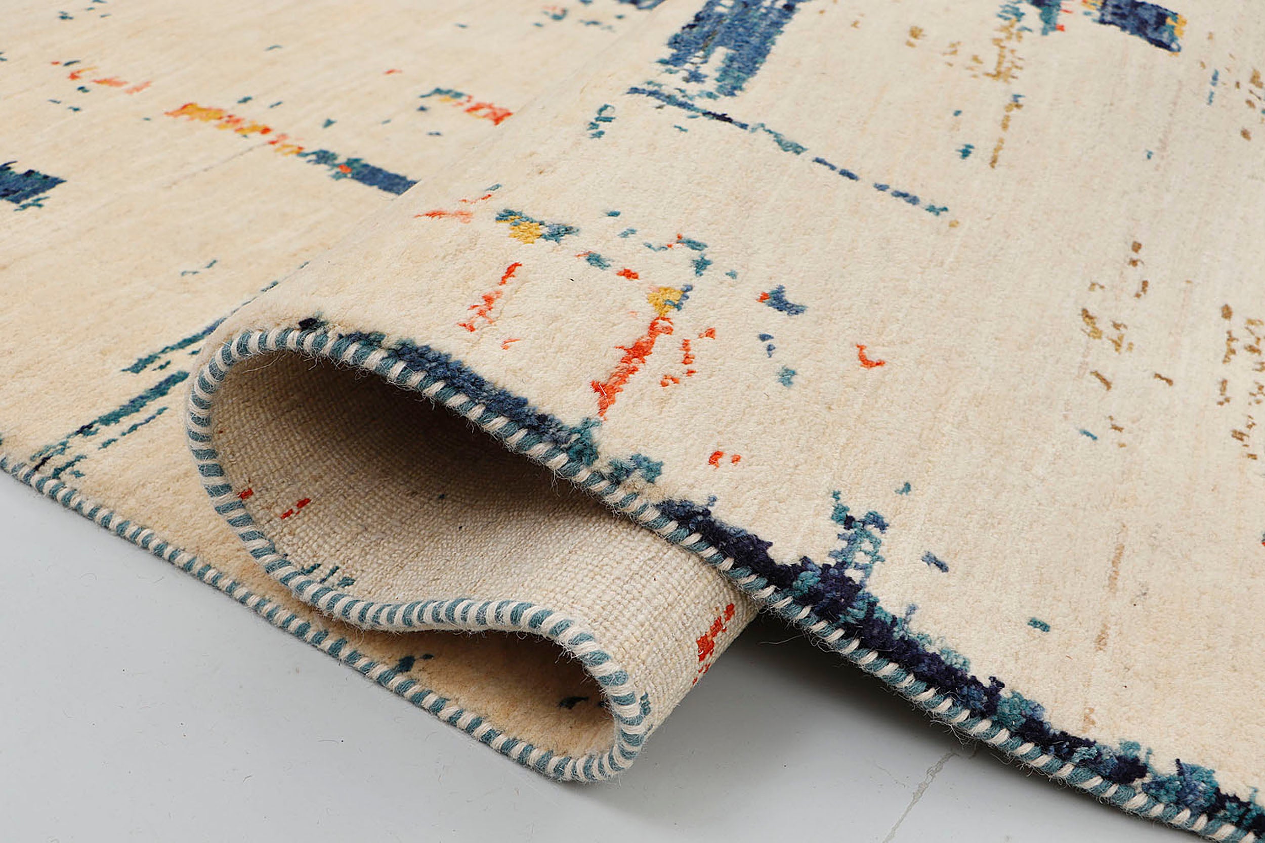 A close-up of a crisp, medium-pile hand-knotted wool rug highlighting the dense, tactile contrast between the geometric blocks of indigo and rust against the light base in a distressed, scraped-paint effect.