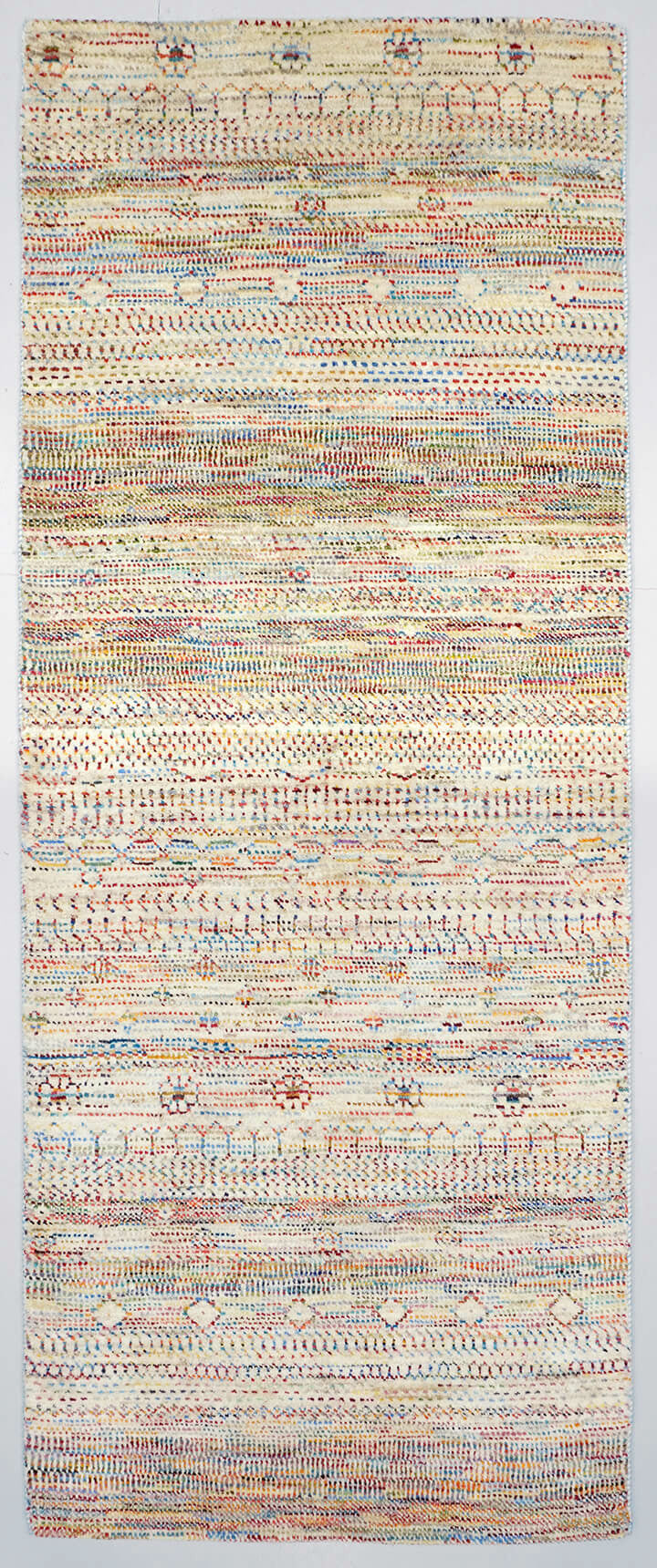 Full view of a natural white hand-knotted Aatish rug featuring rhythmic tiers of multi-colored Rasm motifs