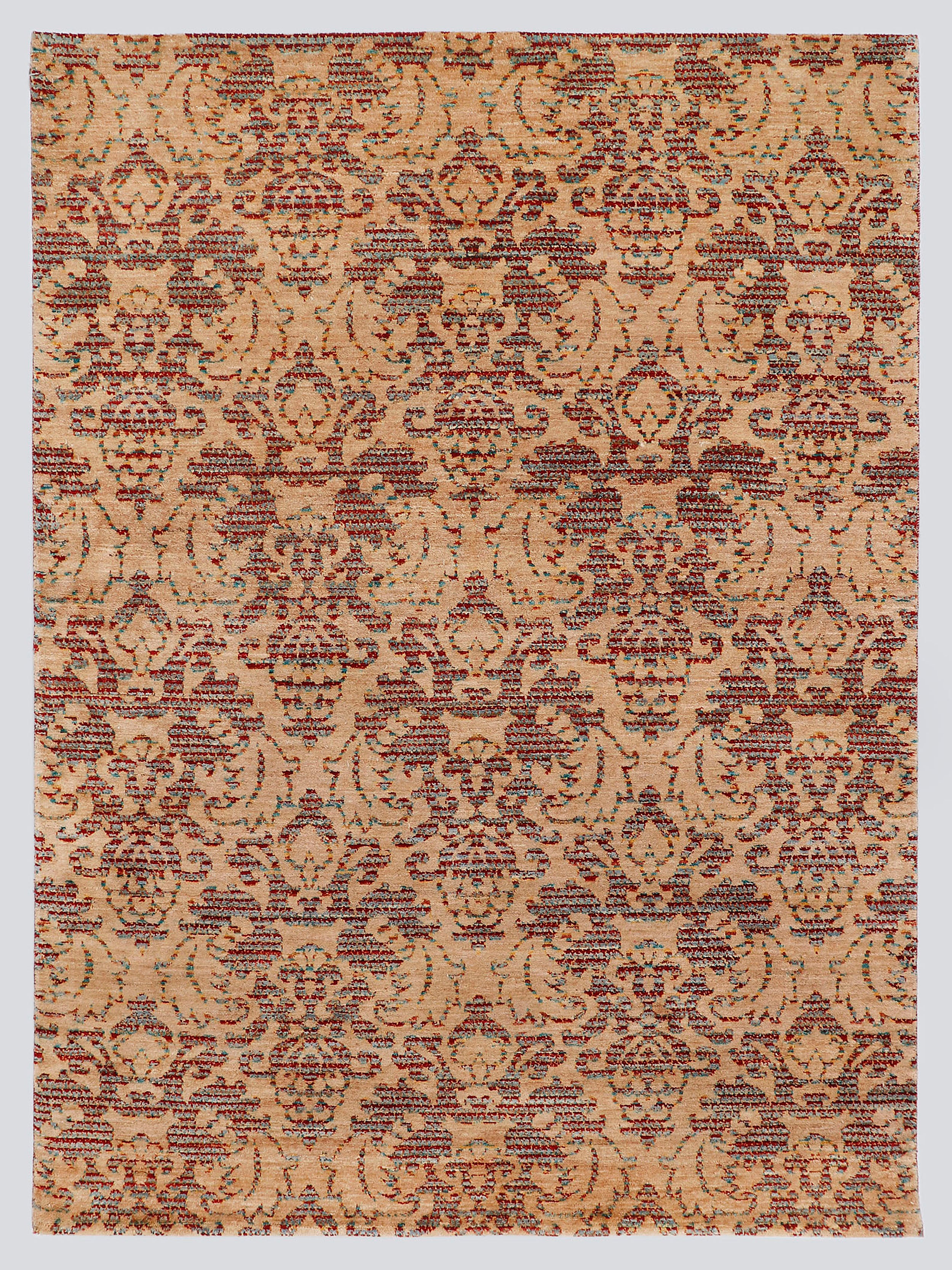 A full view of a modern transitional hand-knotted rug from the Nomad Series, featuring a repeating classical palmette pattern rendered in warm, tie-dyed wool over an amber-sand foundation.