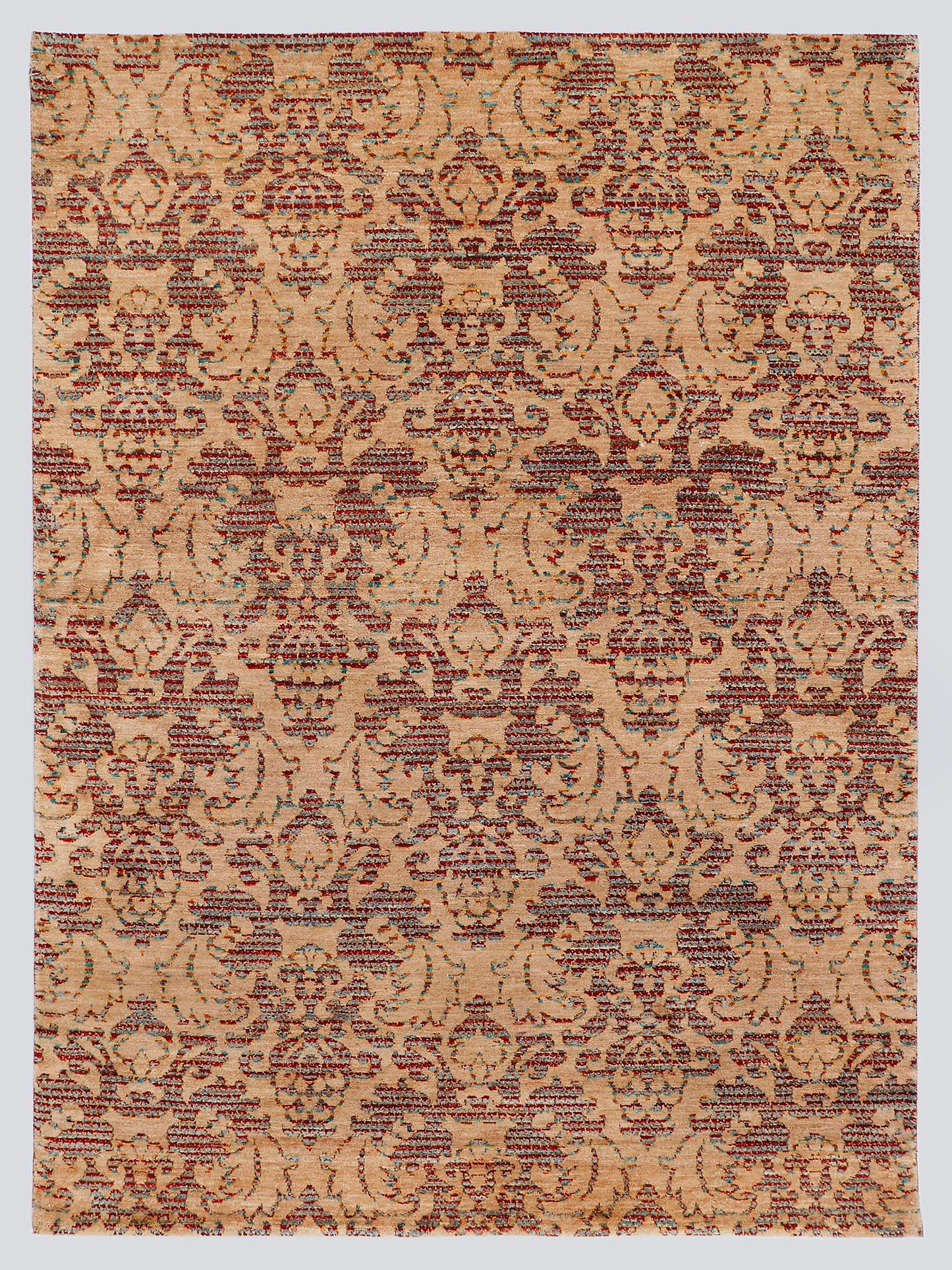A full view of a modern transitional hand-knotted rug from the Nomad Series, featuring a repeating classical palmette pattern rendered in warm, tie-dyed wool over an amber-sand foundation.