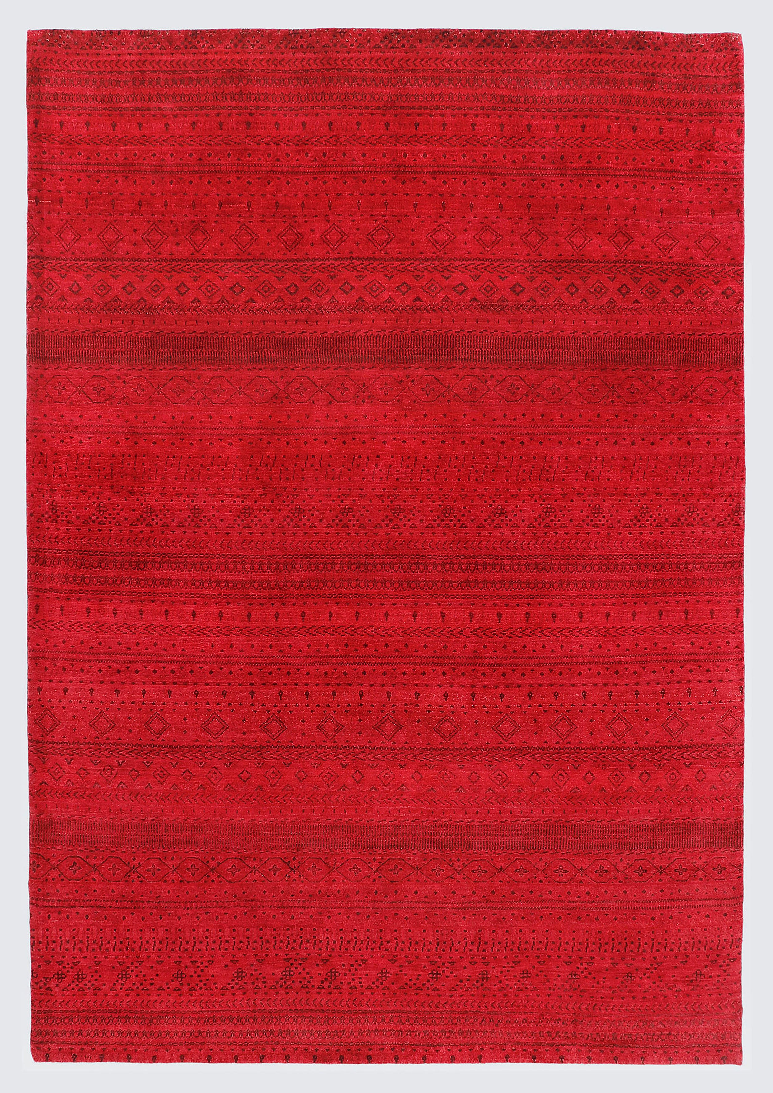 A full view of a vibrant, monochromatic crimson red wool rug featuring subtle, tone-on-tone horizontal bands of miniature Anatolian tribal motifs and geometric patterns.