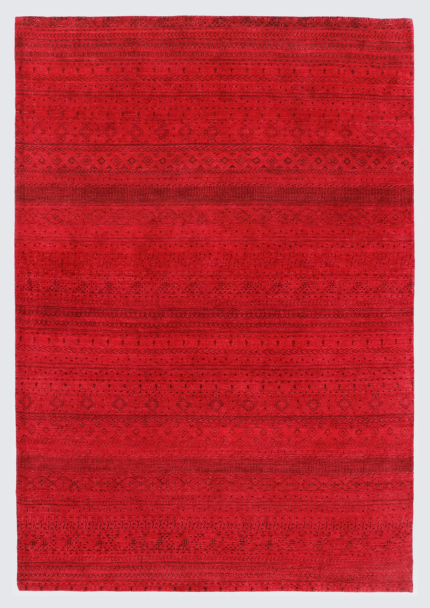 A full view of a vibrant, monochromatic crimson red wool rug featuring subtle, tone-on-tone horizontal bands of miniature Anatolian tribal motifs and geometric patterns.