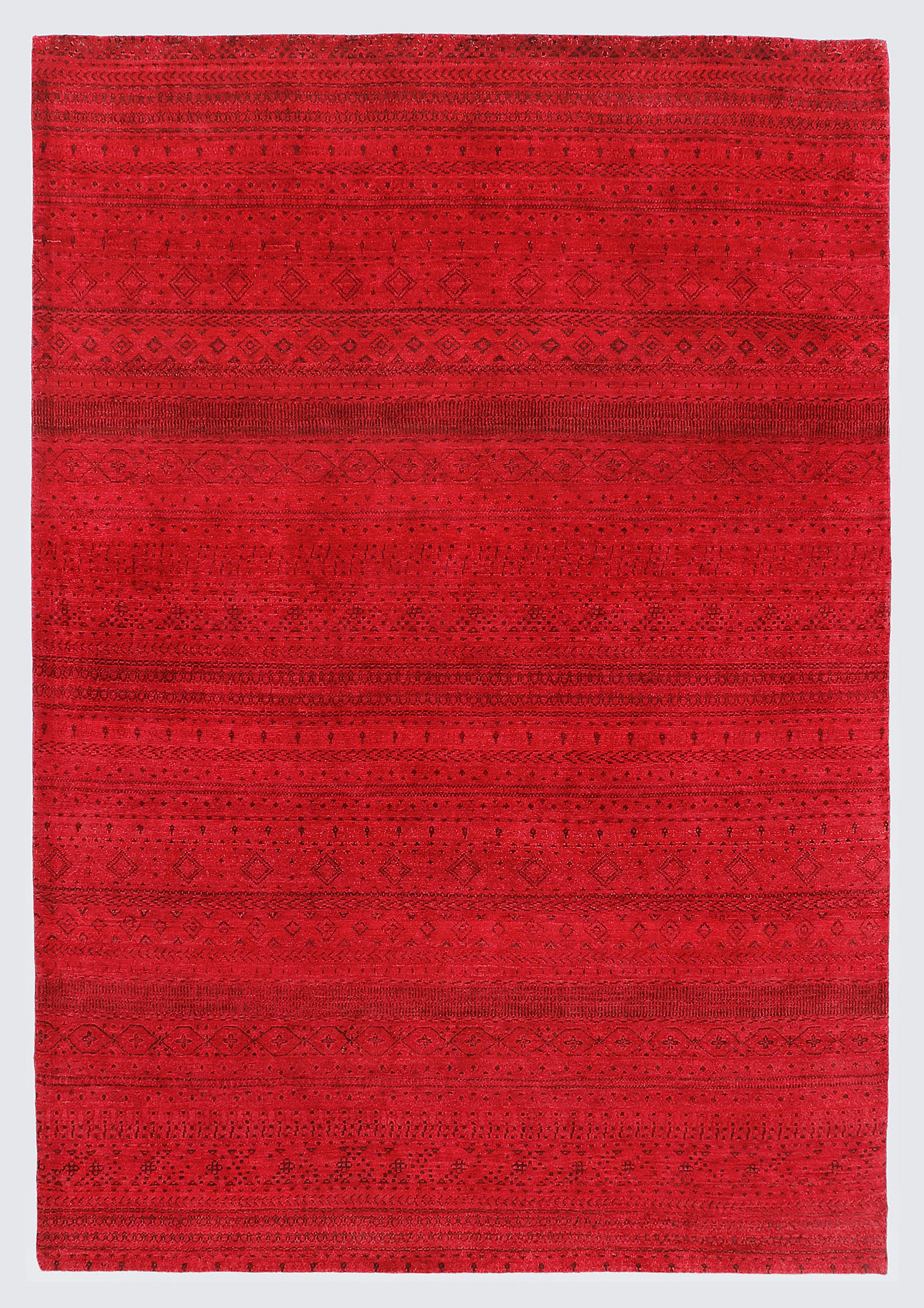 A full view of a vibrant, monochromatic crimson red wool rug featuring subtle, tone-on-tone horizontal bands of miniature Anatolian tribal motifs and geometric patterns.