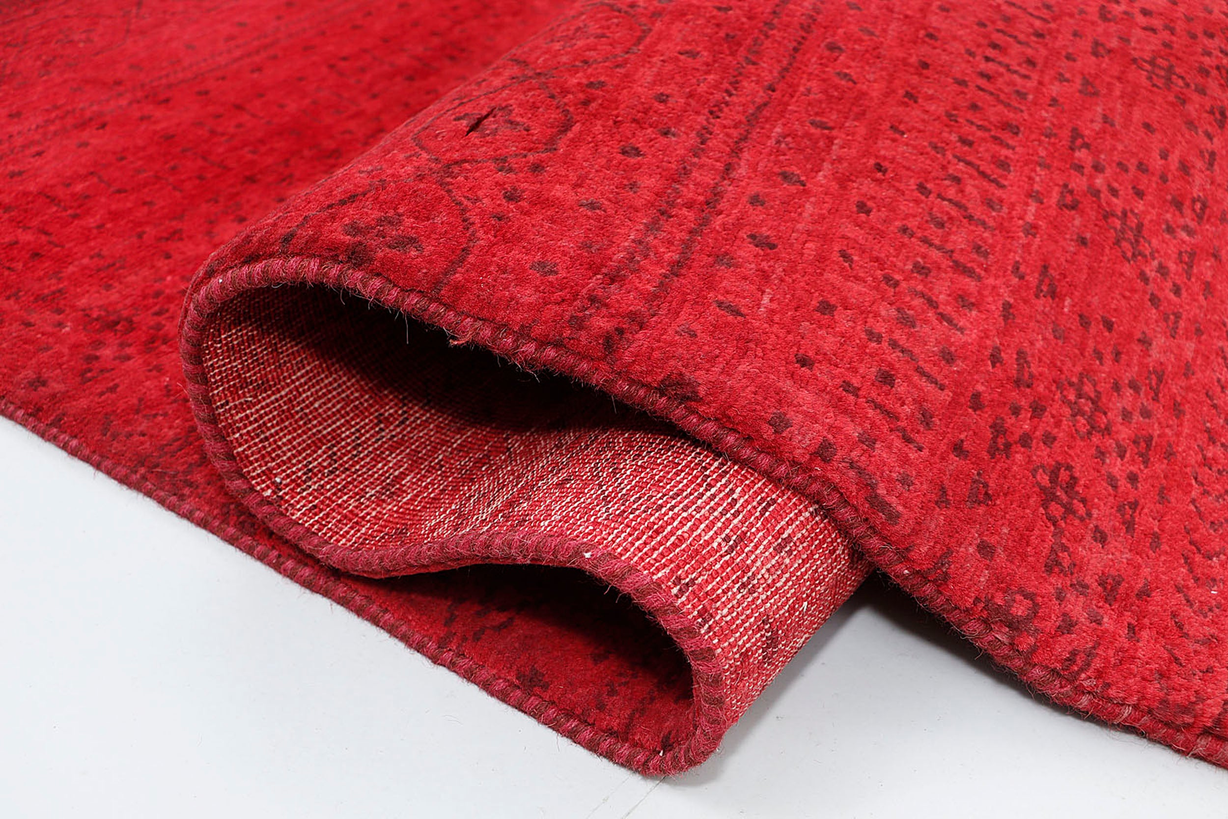 A close-up of a crisp, medium-pile wool rug highlighting the deeply saturated red foundation and intricately woven, subtle burgundy geometric bands.