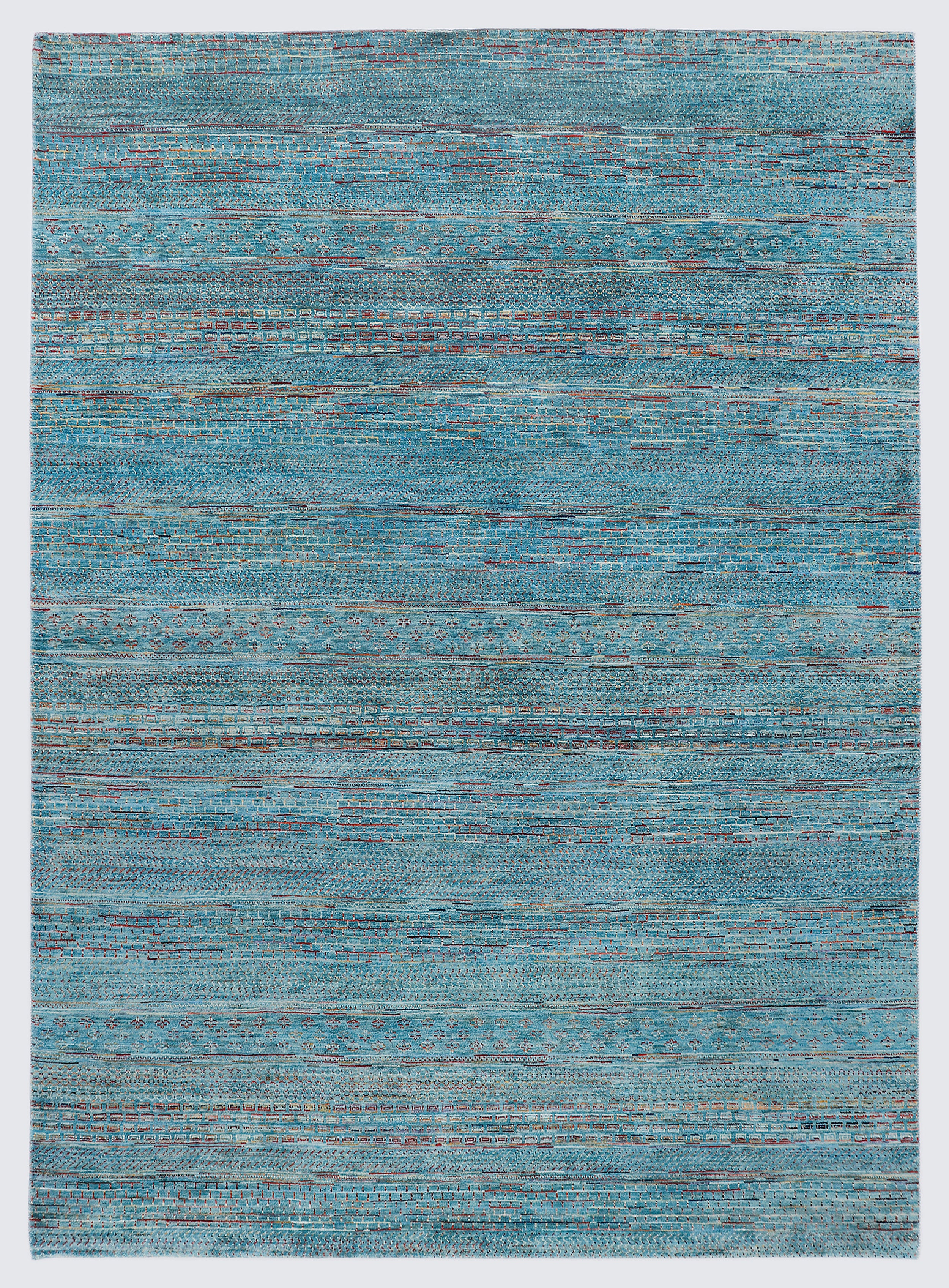 A full view of a vibrant hand-knotted Gabbeh rug from the Aatish collection, featuring horizontal bands of saffron and ivory tribal motifs over a striated sea blue-green foundation.