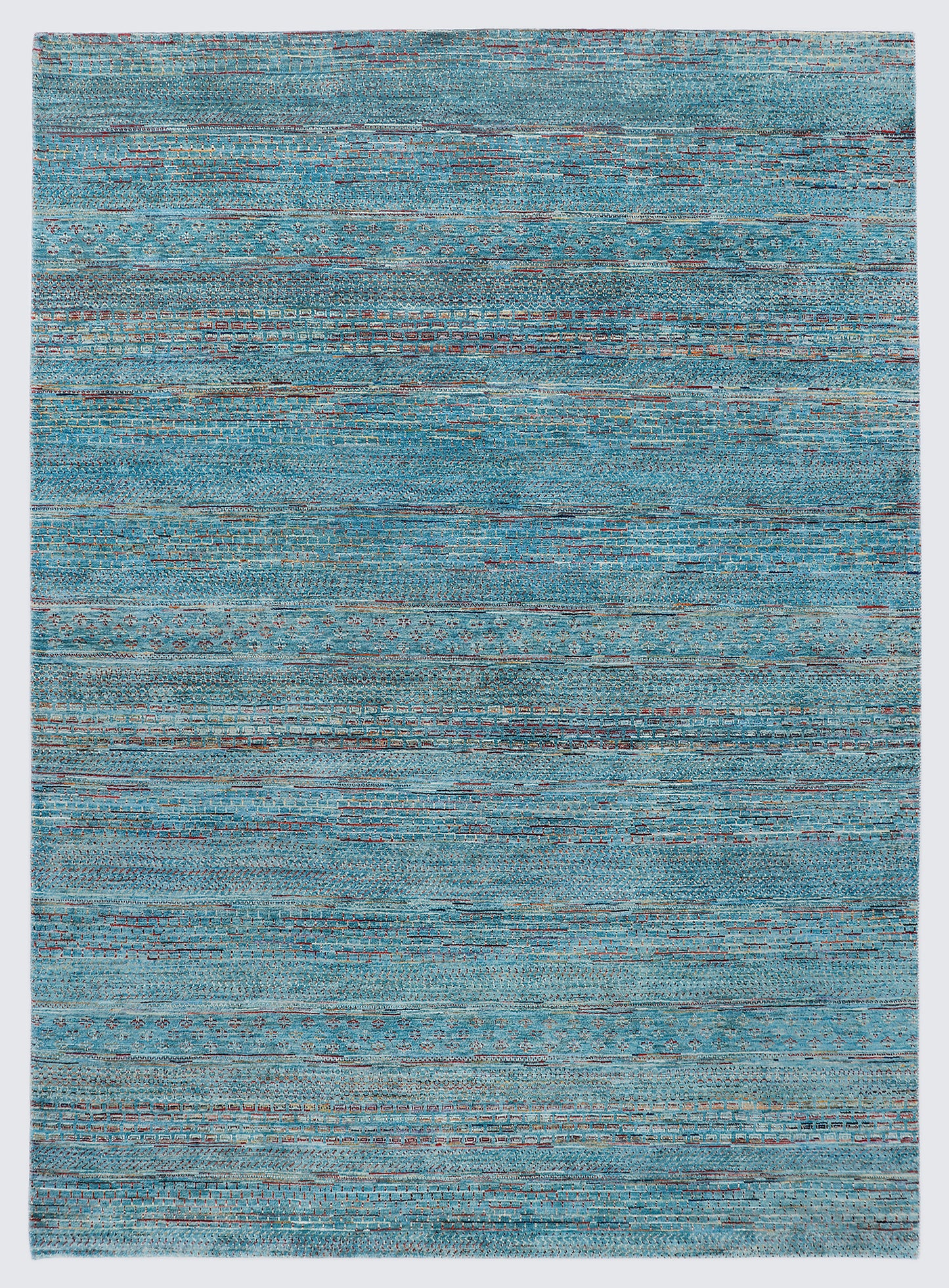 A full view of a vibrant hand-knotted Gabbeh rug from the Aatish collection, featuring horizontal bands of saffron and ivory tribal motifs over a striated sea blue-green foundation.