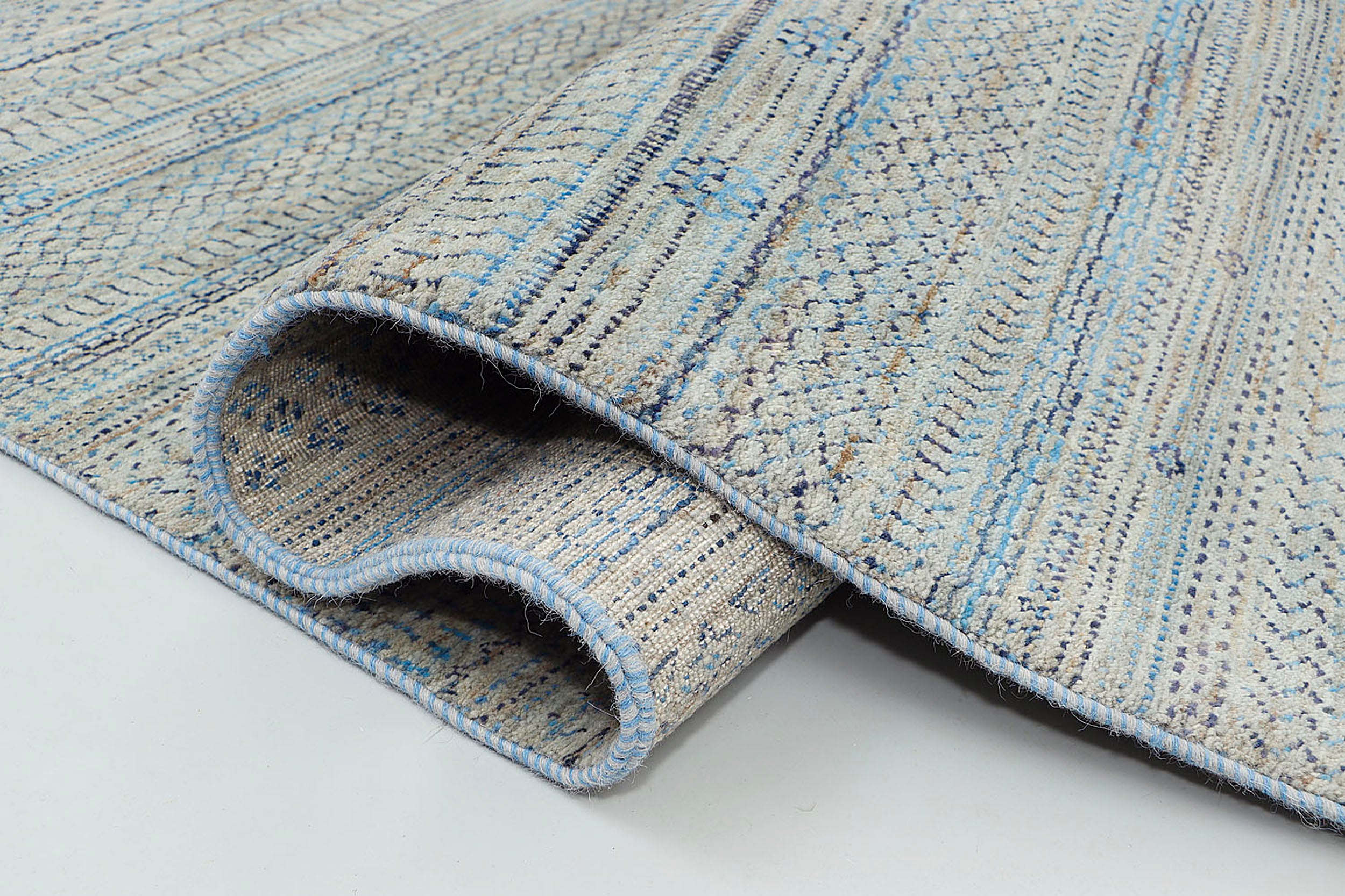 A close-up of a thick-pile wool rug highlighting the natural abrash and silvery-grey tonal shifts of the base wool, contrasted by unique, tie-dyed nomadic symbols.