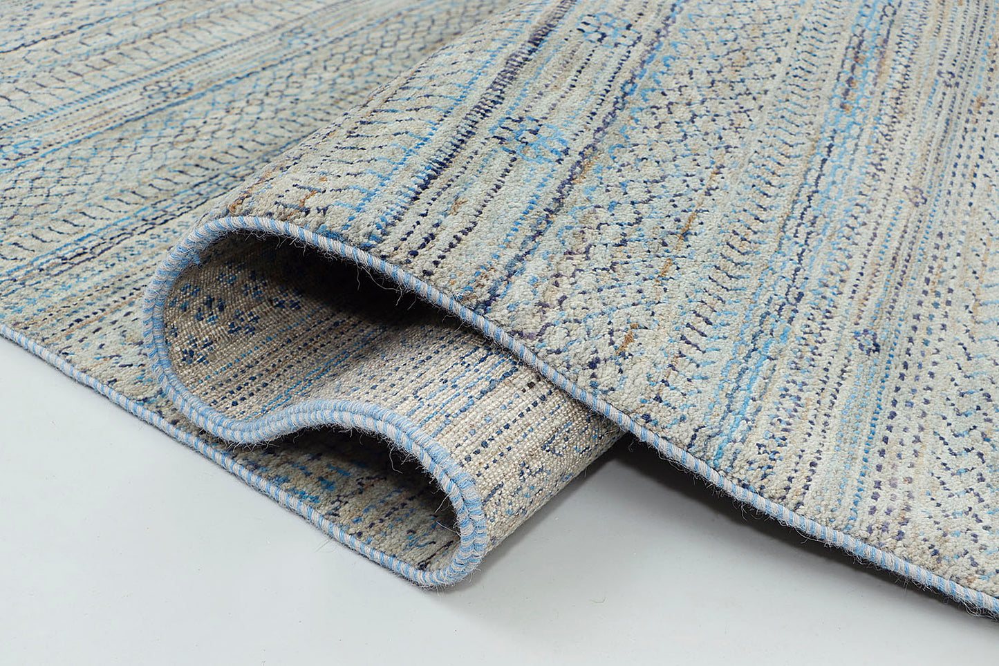 A close-up of a thick-pile wool rug highlighting the natural abrash and silvery-grey tonal shifts of the base wool, contrasted by unique, tie-dyed nomadic symbols.