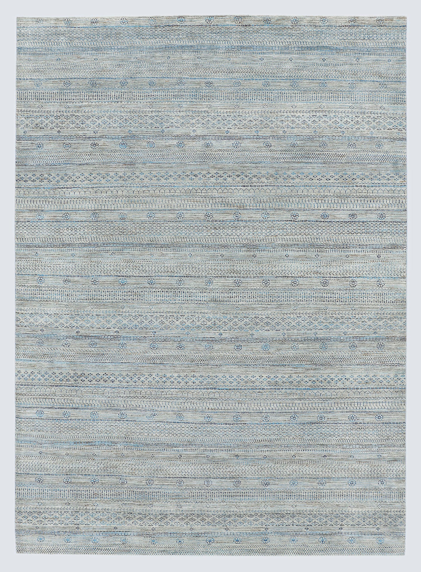 A full view of a sophisticated silver-grey hand-knotted Gabbeh rug from the Aatish collection, featuring horizontal bands of tie-dyed tribal motifs over a textured, natural wool foundation.