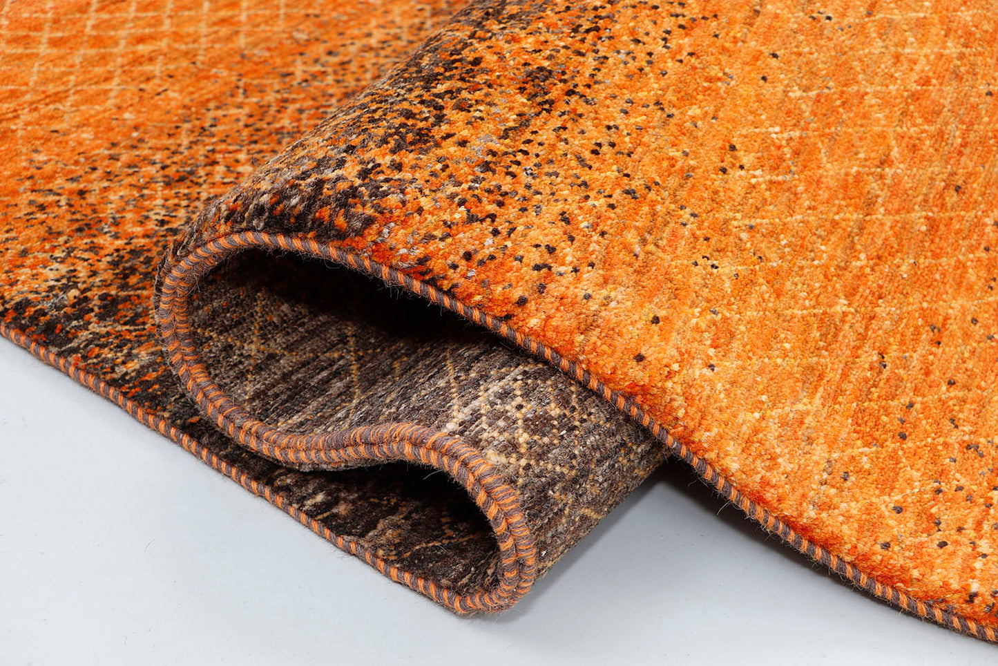 A close-up of a crisp, medium-pile wool rug highlighting subtle, tone-on-tone woven textures and a continuous ghosted diamond pattern within a vibrant orange and dark brown base.
