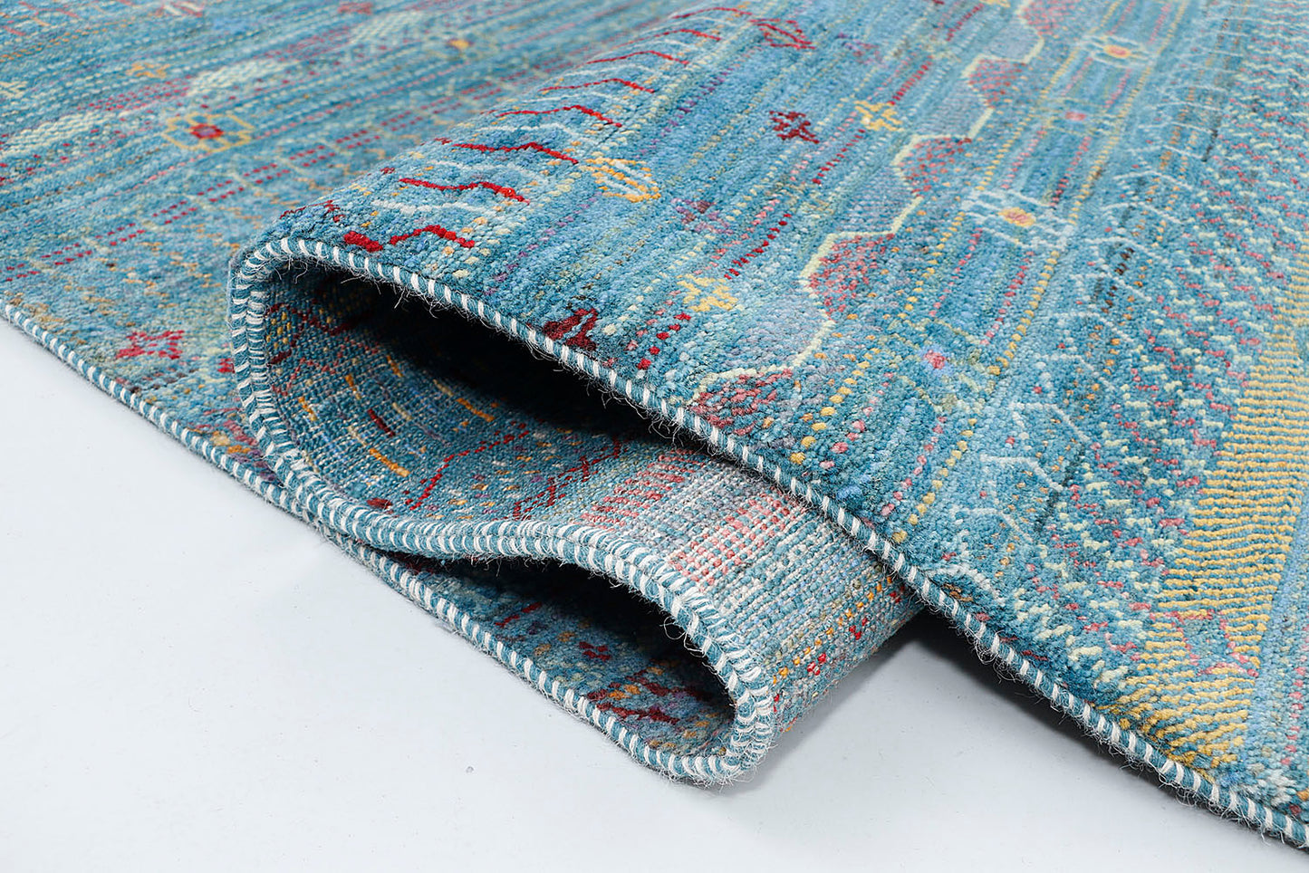 A close-up of a thick-pile wool rug highlighting the dense texture and the rhythmic, musical rows of colorful nomadic symbols against an aquatic background
