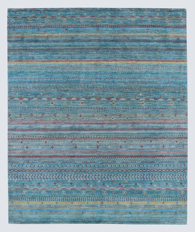 A full view of a vibrant hand-knotted Gabbeh rug from the Aatish collection, featuring horizontal bands of saffron and ivory tribal motifs over a striated sea-blue-green foundation.