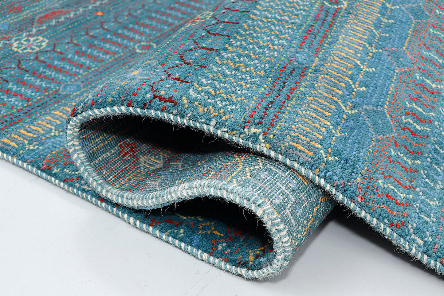 A close-up of a crisp hand-knotted wool rug highlighting the meticulous detail of tiny, repeating nomadic motifs arranged in horizontal stripes against a vibrant blue background.
