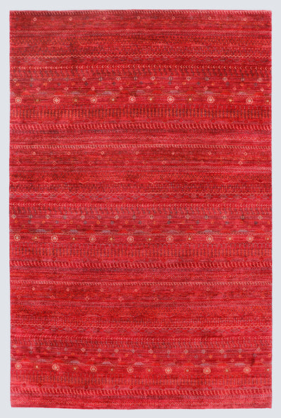 A full view of a vibrant red hand-knotted Gabbeh rug from the Aatish collection, featuring horizontal bands of gold and ivory tribal motifs over a saturated cinnabar foundation.