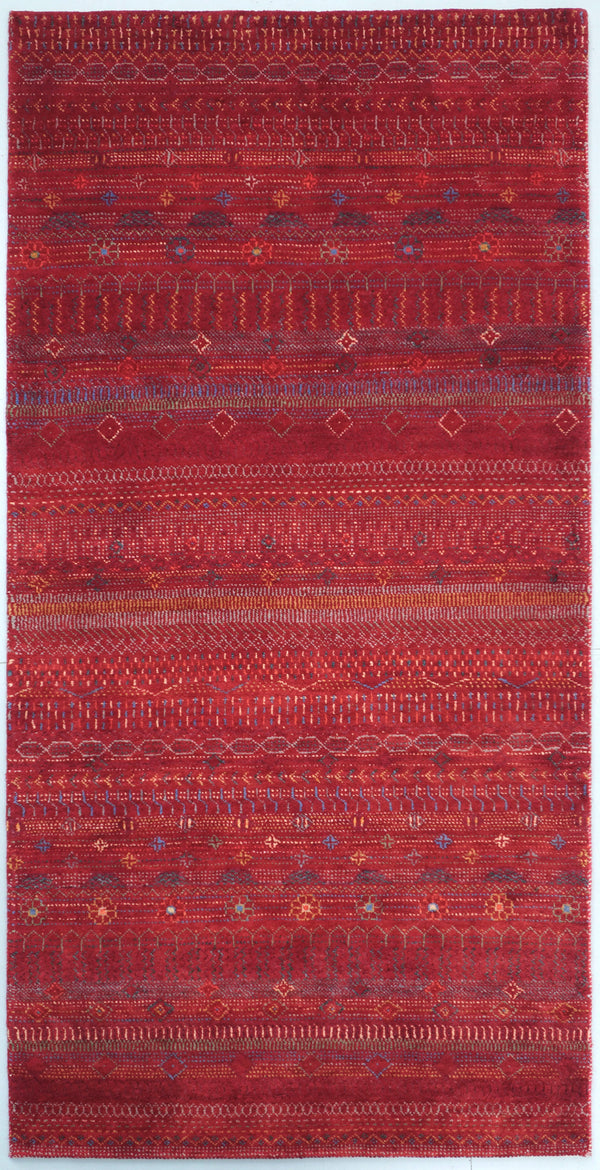 Hand-knotted modern Gabbeh rug in rich red wool featuring intricate horizontal bands and tribal motifs, captured in natural daylight.
