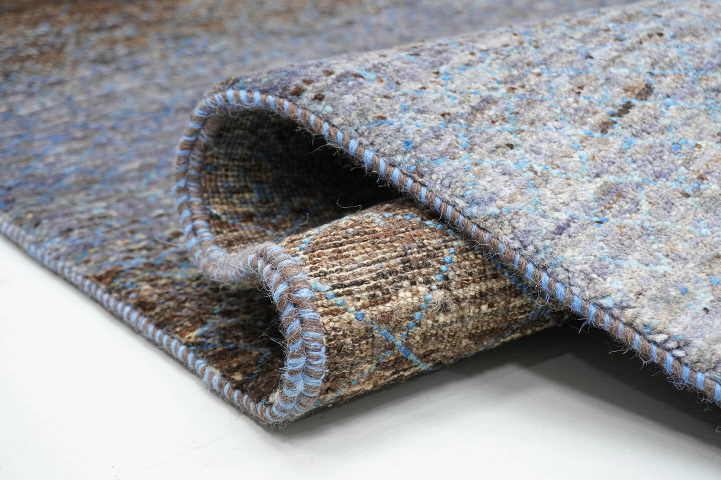 Close-up of the plush, natural brown wool pile and atmospheric blue levels of the Ebony Sarab rug