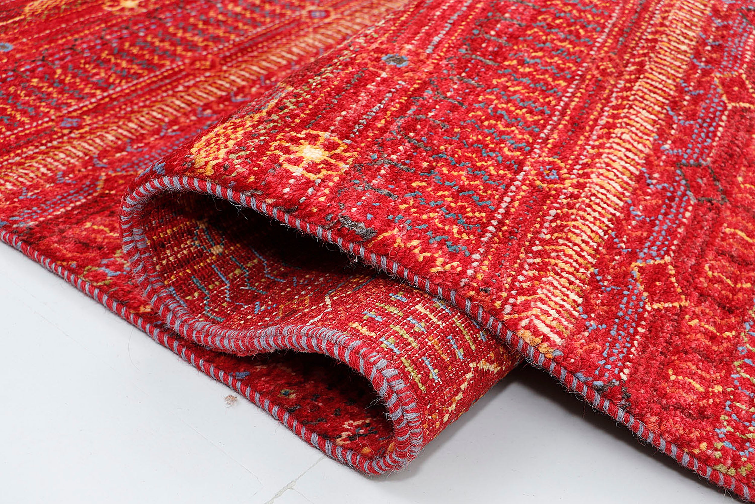 A close-up of a plush wool rug highlighting the dense, hand-knotted texture and the rhythmic, multi-colored geometric symbols woven into the warm, kiln-fired base.