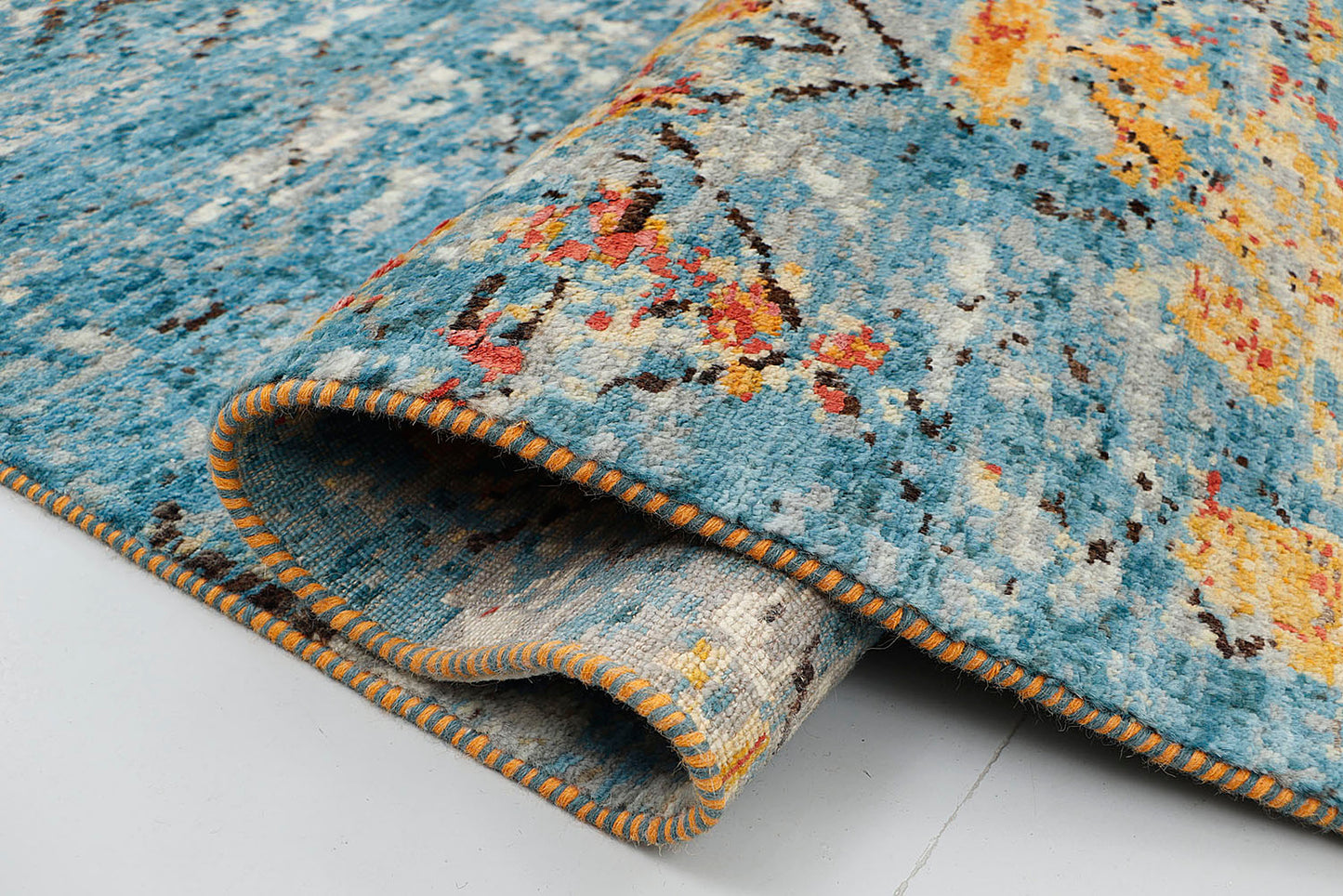 A close-up of a crisp, medium-pile hand-knotted wool rug highlighting the dense contrast between the vivid blue and copper yarns in a distressed, erased motif design.
