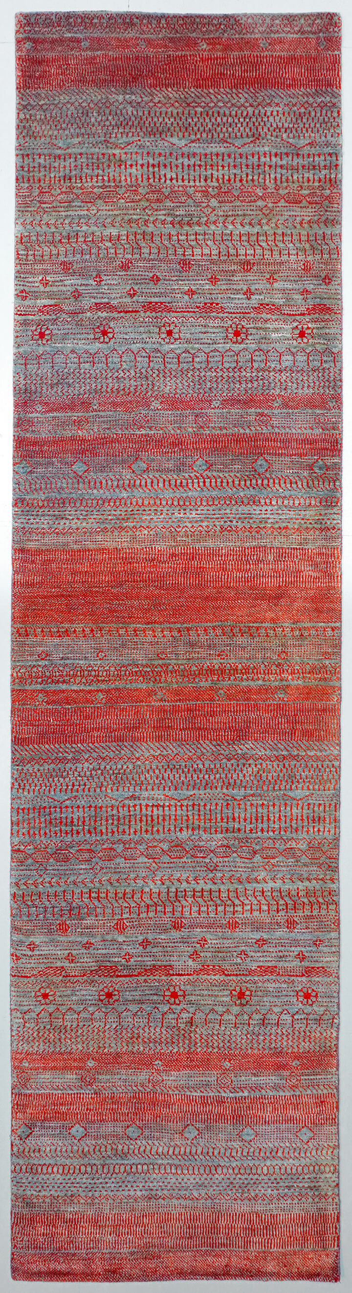 Full view of a Graphite grey hand-knotted Aatish rug featuring vibrating red and orange Pulse motifs.