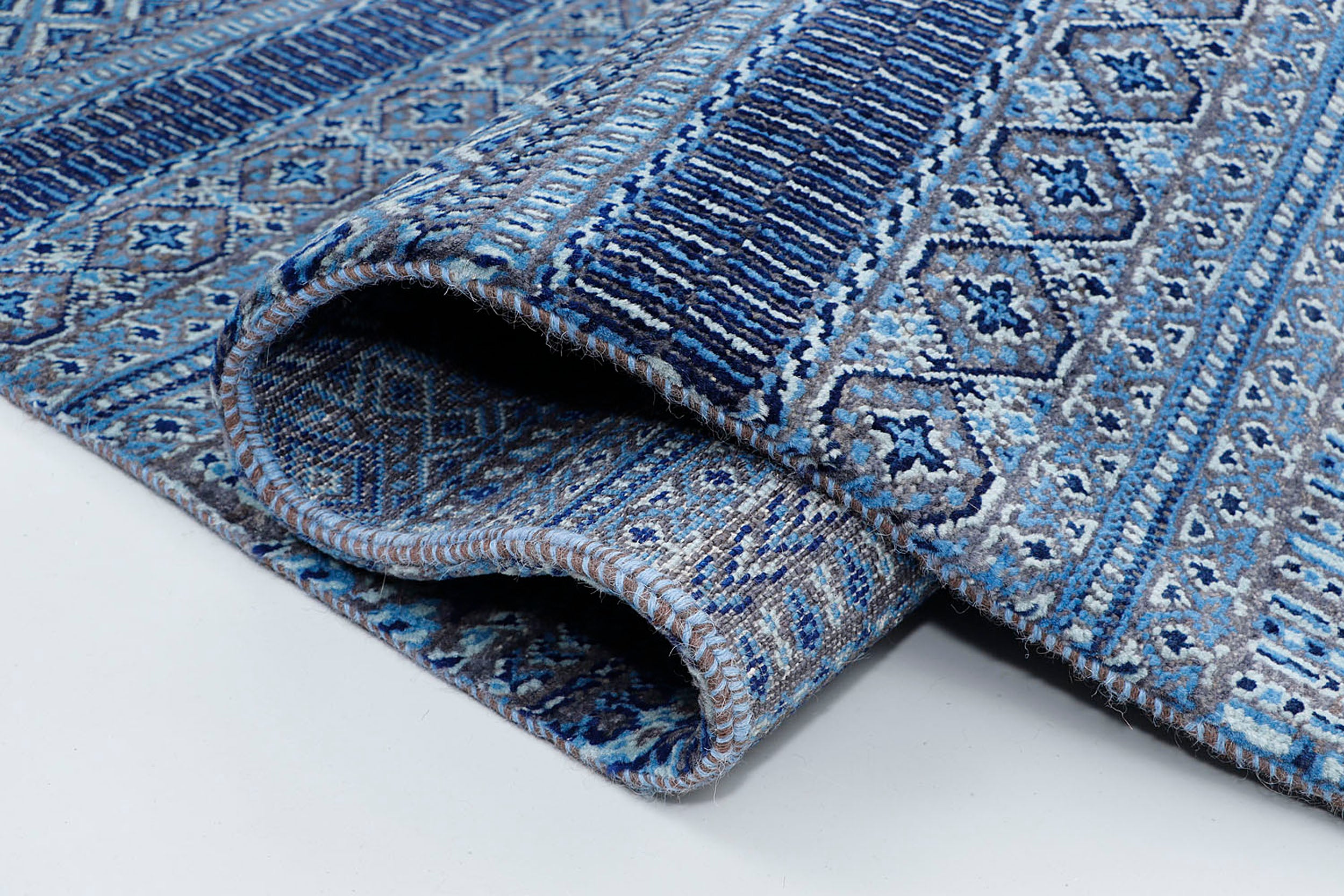 A close-up of a crisp, medium-pile wool rug highlighting intricately woven horizontal stripes filled with tiny geometric diamond patterns on a deep blue base.