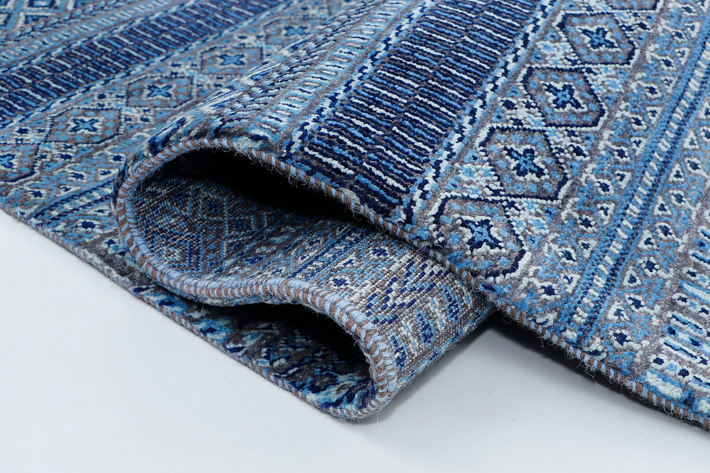 A close-up of a crisp, medium-pile wool rug highlighting intricately woven horizontal stripes filled with tiny geometric diamond patterns on a deep blue base.