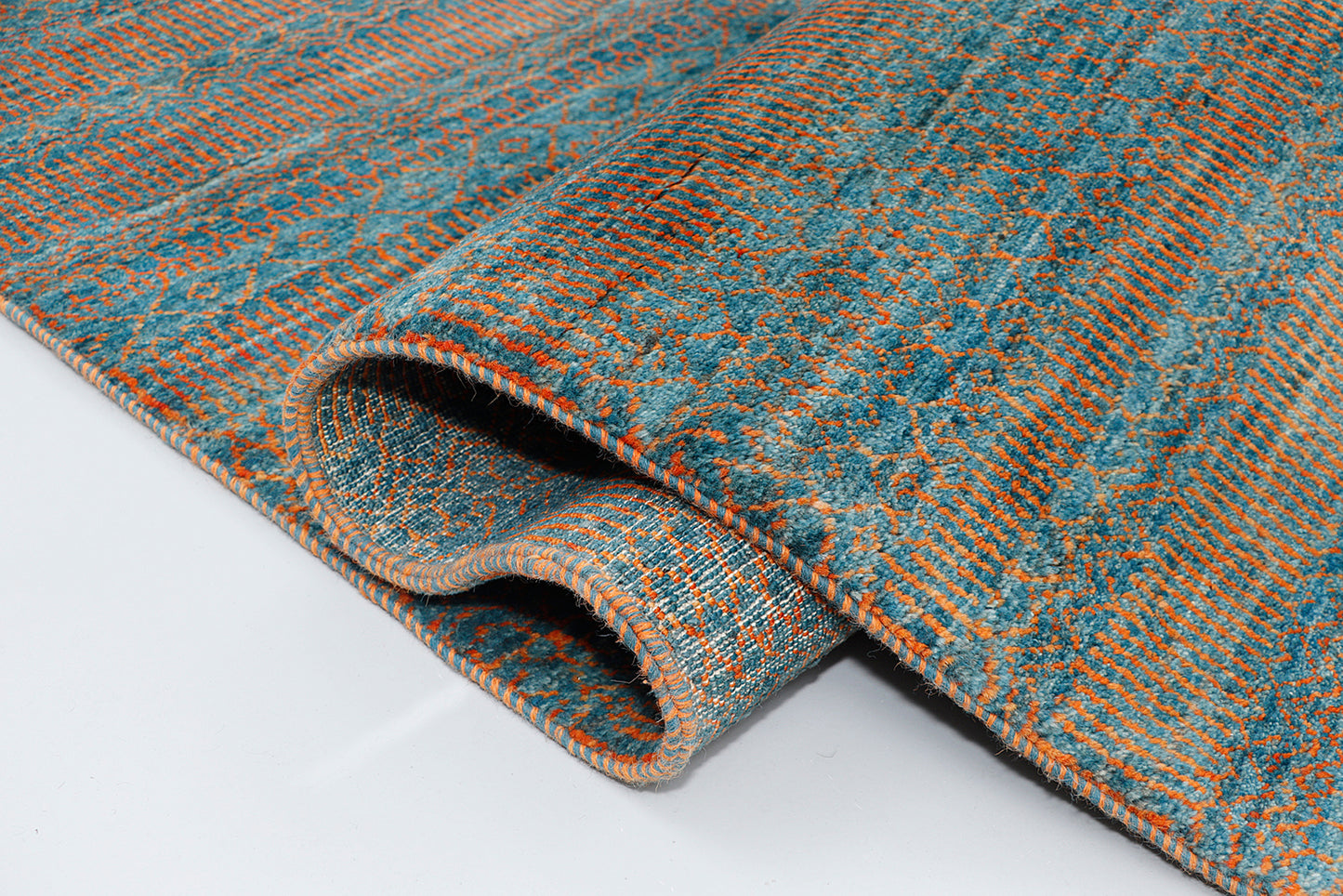 A full view of a vibrant hand-knotted double-knot Gabbeh rug from the Aatish collection, featuring horizontal bands of variegated orange tribal motifs over a textured malachite blue-green foundation.