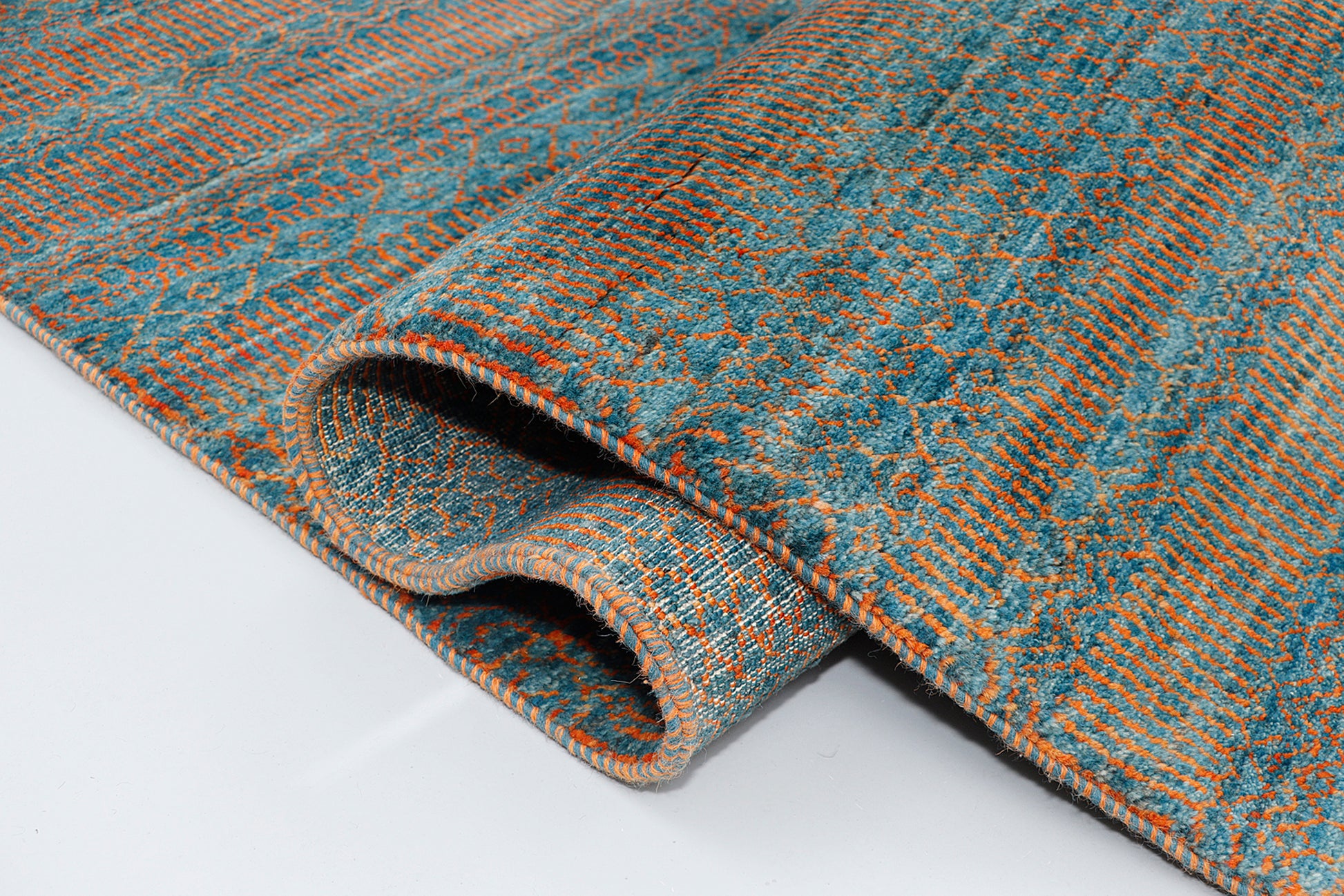 A full view of a vibrant hand-knotted double-knot Gabbeh rug from the Aatish collection, featuring horizontal bands of variegated orange tribal motifs over a textured malachite blue-green foundation.