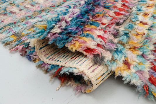 A close-up highlighting the extra-long, plush shag pile texture of a hand-knotted Moroccan rug, detailing the thick, tactile nature of the colorful wool yarn.