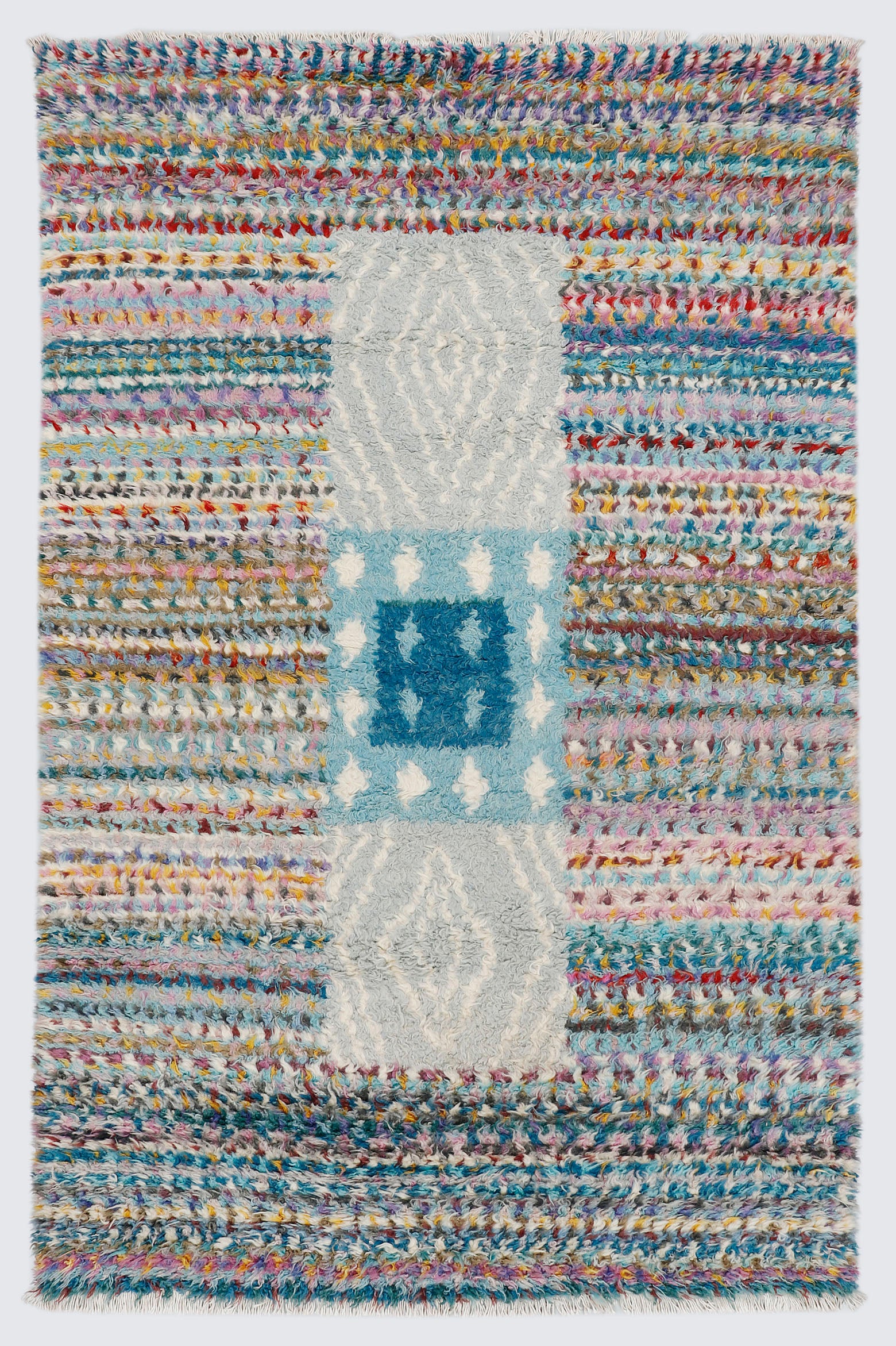 A full view of a hand-knotted, shag-pile Moroccan style rug featuring vibrant, multi-colored horizontal stripes and a contrasting central vertical block pattern in light blue, dark cerulean, and heather grey.
