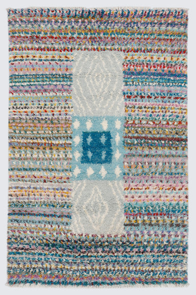 A full view of a hand-knotted, shag-pile Moroccan style rug featuring vibrant, multi-colored horizontal stripes and a contrasting central vertical block pattern in light blue, dark cerulean, and heather grey.