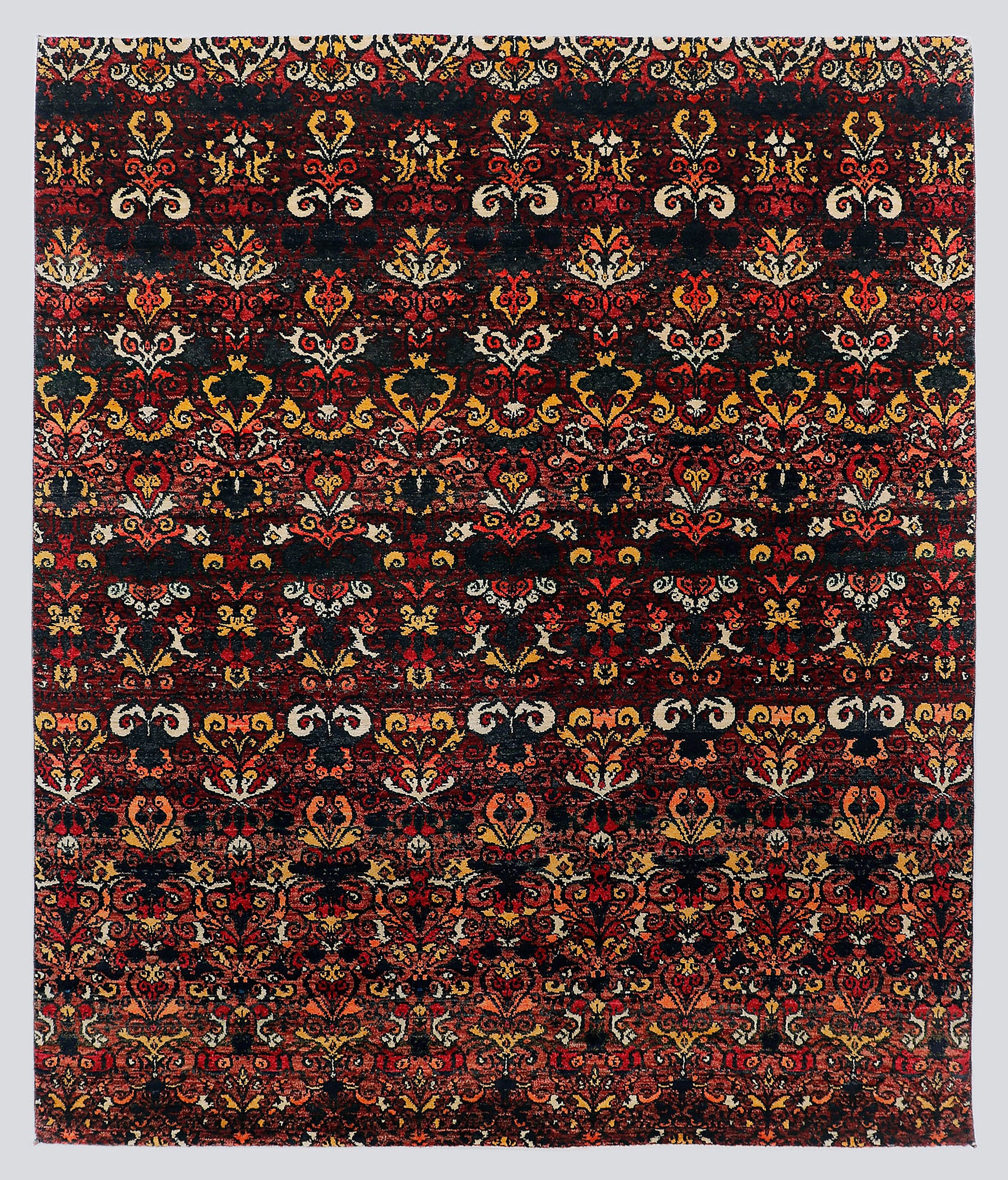 A full view of a dramatic, premium hand-knotted rug featuring repeating classical floral motifs in vivid garnet red and saffron gold against a deep midnight black foundation.