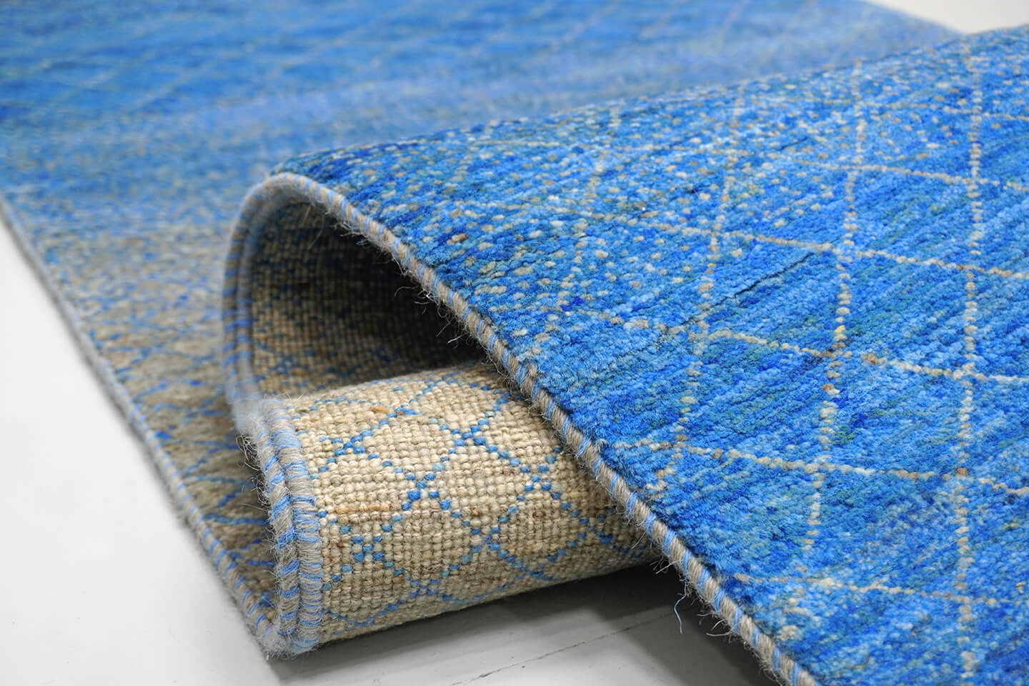 Close-up of the plush, unpigmented wool pile and vibrating blue color transitions of the Natural Sama rug.