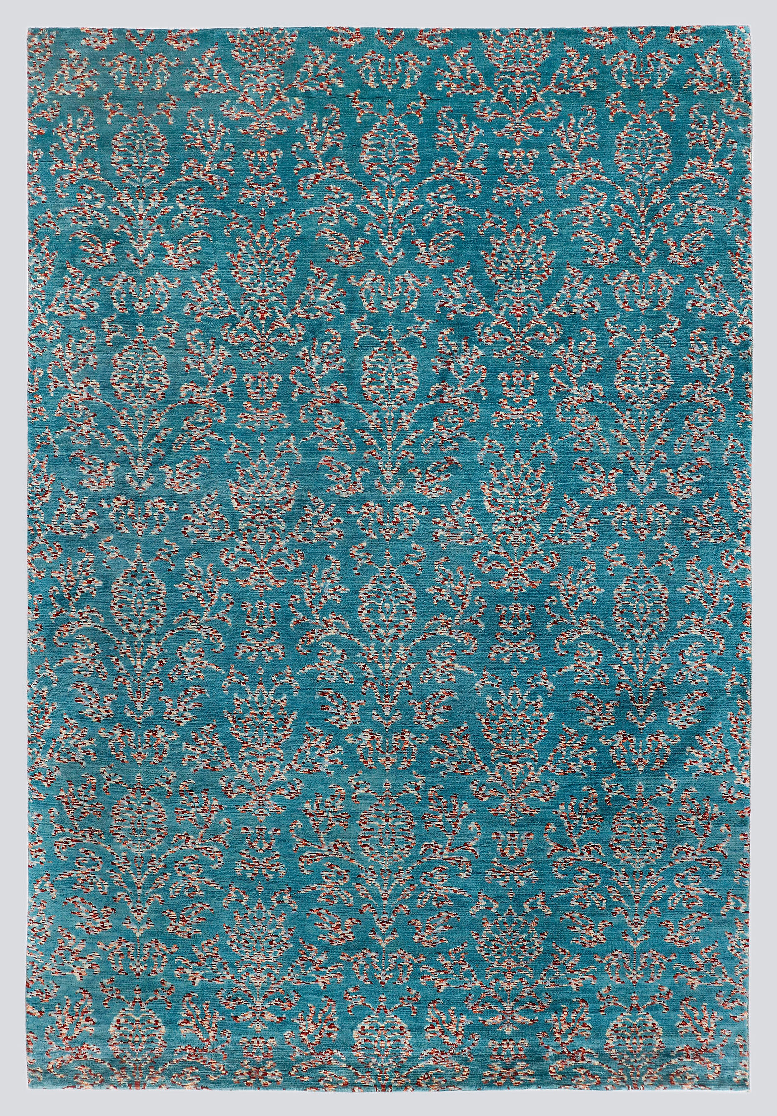 A full view of a vibrant, hand-knotted transitional rug from the Nomad Series, featuring a repeating classical trellis pattern rendered in tie-dyed wool over a vivid peacock-blue foundation.