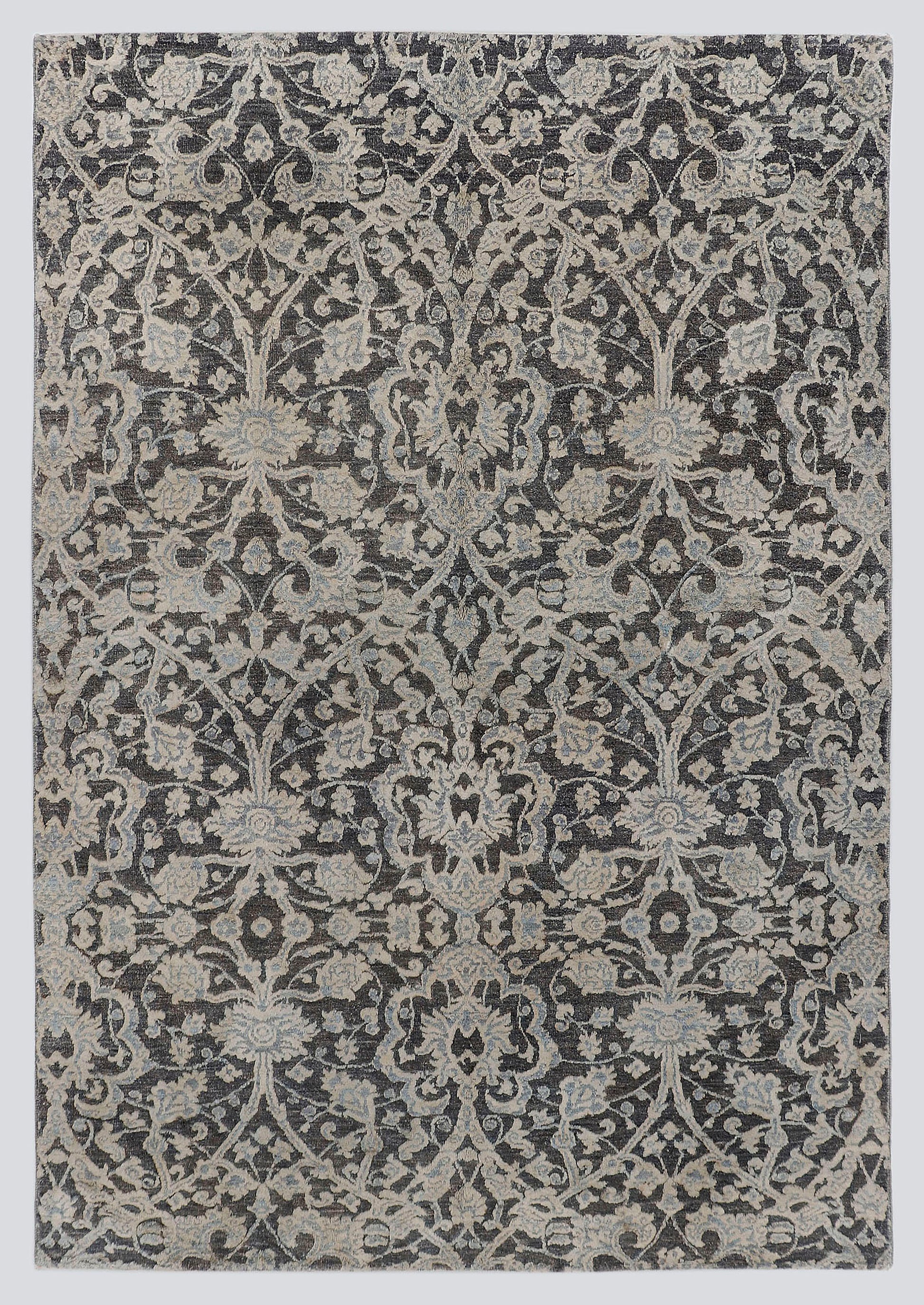 A full view of a luxury hand-knotted rug from the Nomad Series, featuring a high-low pile design with raised, silvery-ivory floral vines stretching over a deep charcoal background.