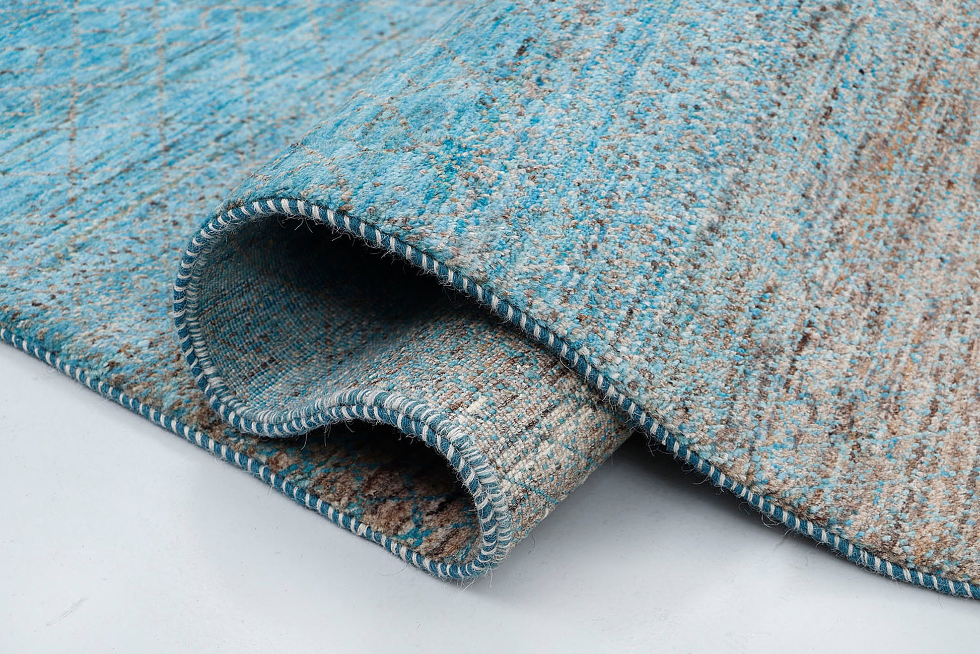 A high-resolution close-up highlighting the double-knot texture and the natural "abrash" effect of the variegated blue and natural silver wool.