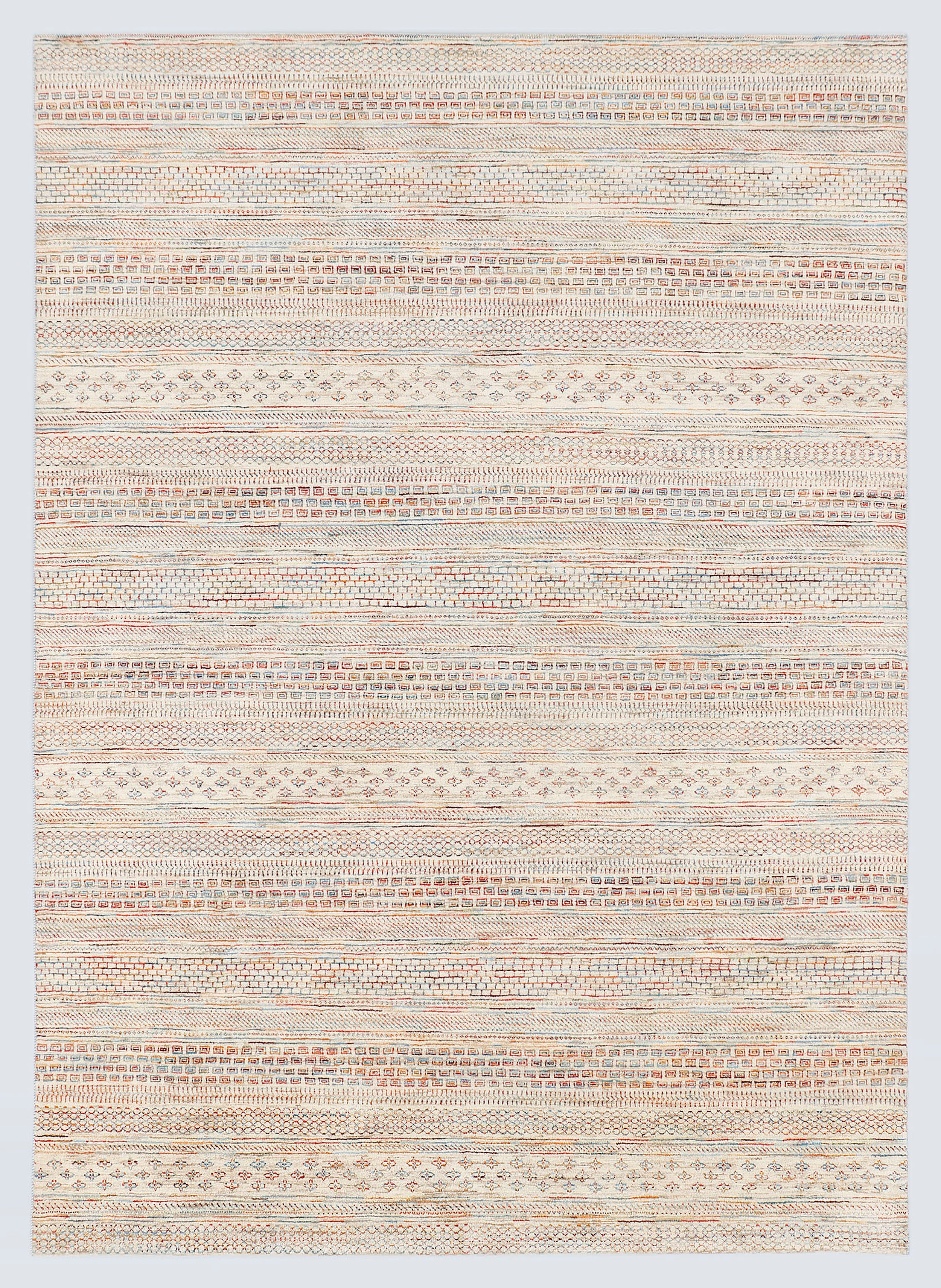 A full view of a hand-knotted wool rug from the Aatish Collection featuring dense horizontal bands of miniature tribal motifs in soft terracotta and powder blue against a luminous ivory foundation.