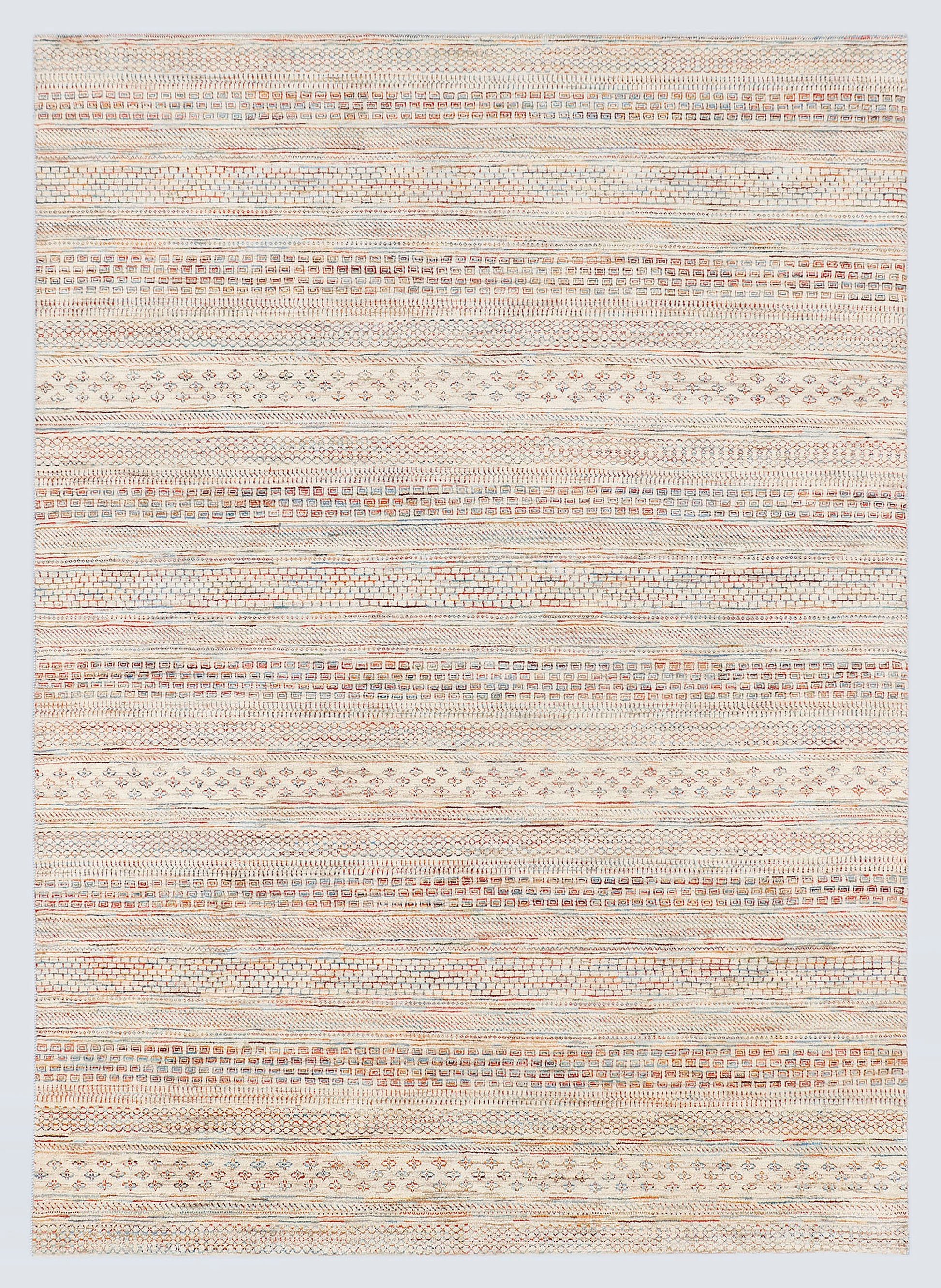 A full view of a hand-knotted wool rug from the Aatish Collection featuring dense horizontal bands of miniature tribal motifs in soft terracotta and powder blue against a luminous ivory foundation.