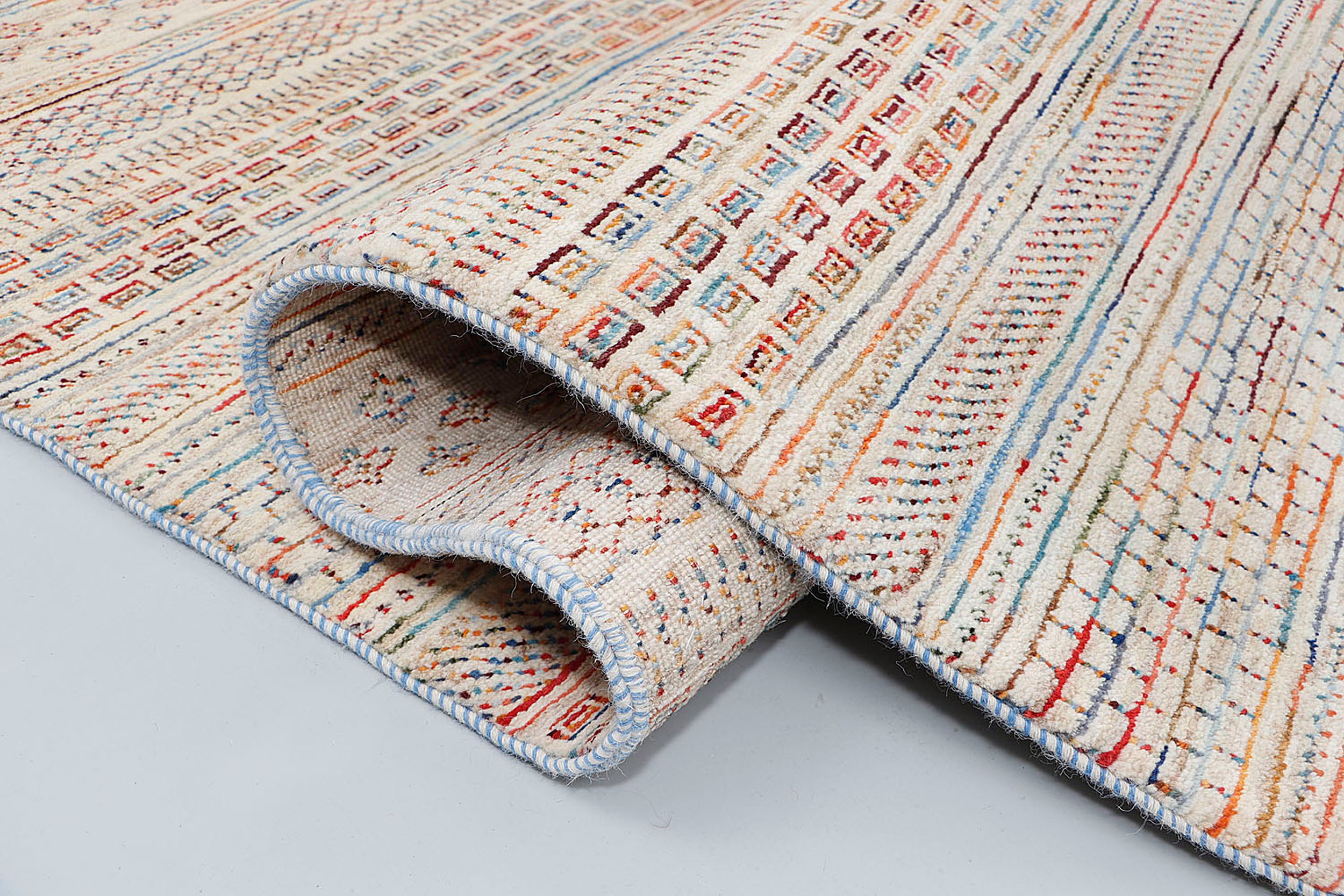 A close-up of a crisp, medium-pile wool rug showcasing precise Persian double knotting, highlighting intricately woven horizontal stripes filled with tiny geometric patterns on a light ivory base.
