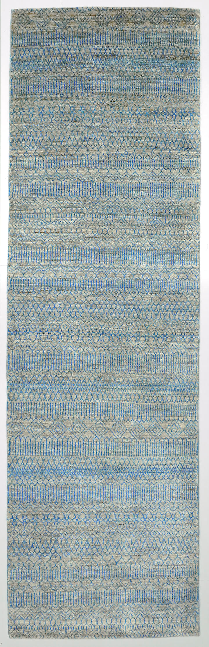 Full view of a silver grey hand-knotted Aatish rug featuring shifting, tie-and-dye blue Falak motifs.