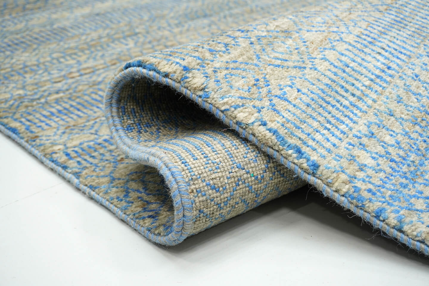 Close-up of the plush silver grey wool pile and the vibrating blue color transitions of the Silver Falak rug