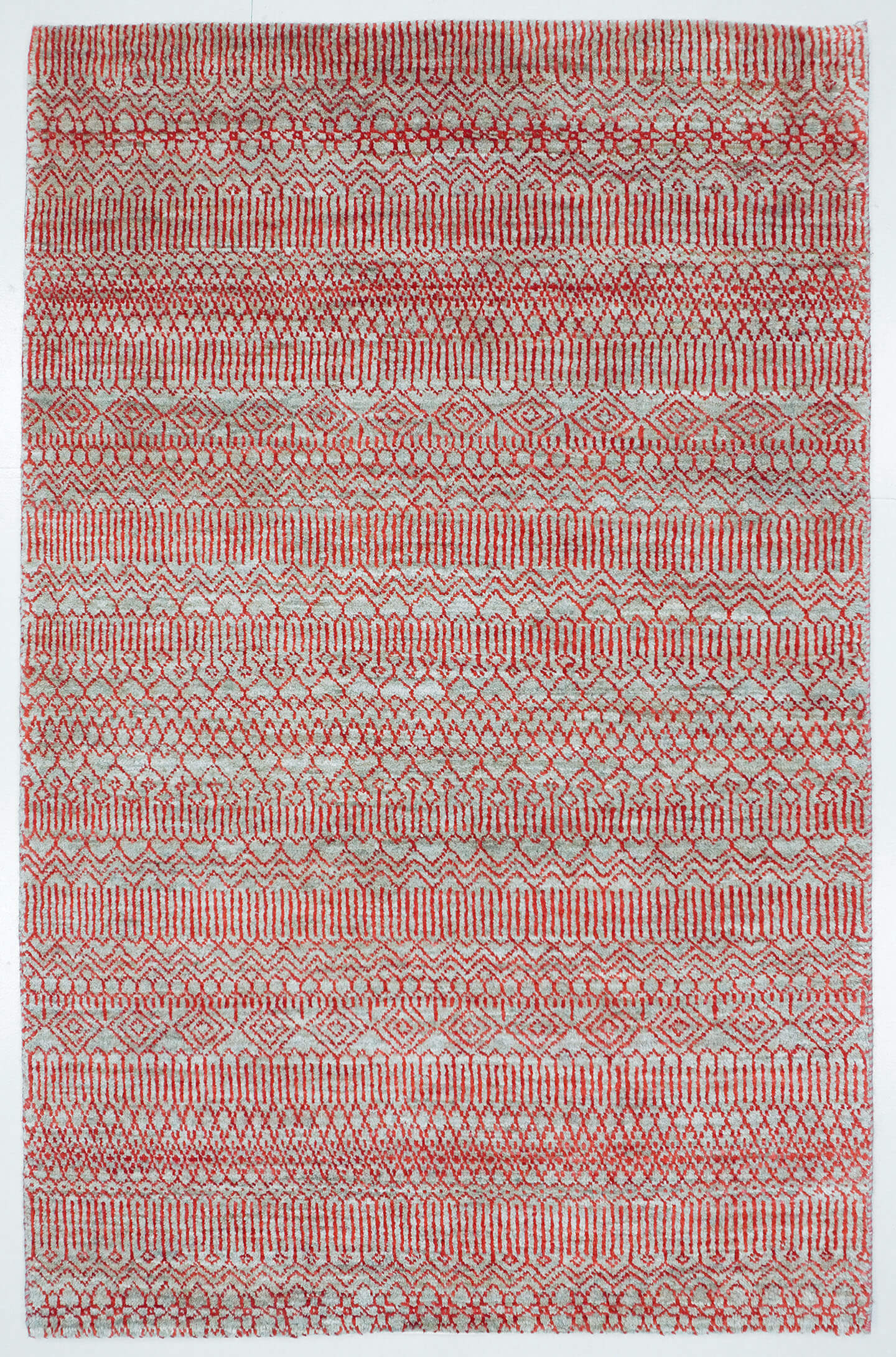 Full view of a silver grey hand-knotted Aatish rug featuring a vibrating red Jali lattice.