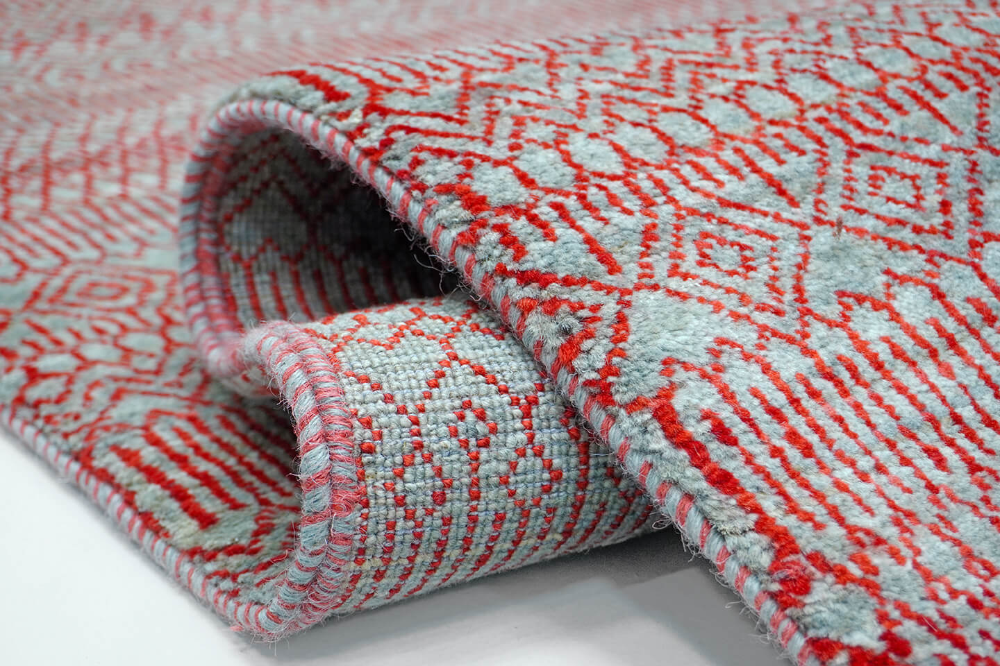 Close-up of the plush silver wool pile and vibrating red heritage lattice levels of the Silver Jali rug