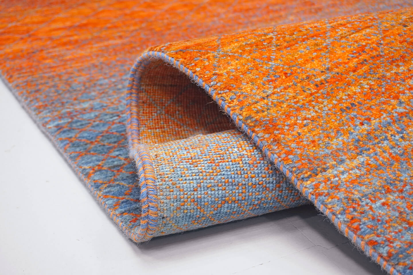 Close-up of the plush slate grey wool pile and the multi-tonal orange vibration of the Slate Kohl rug