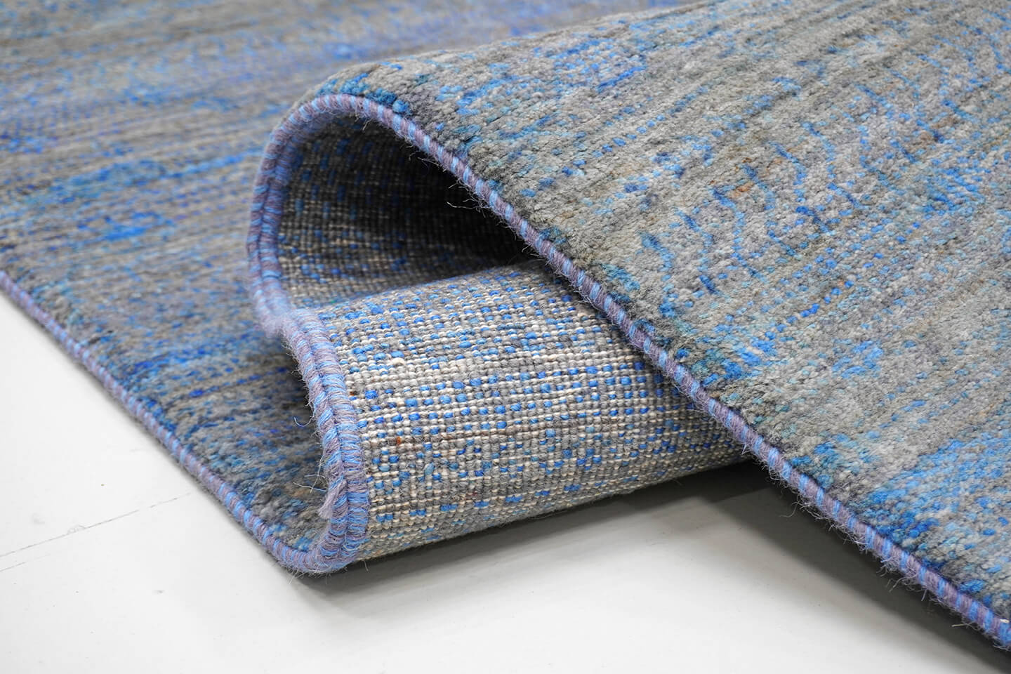 Close-up of the plush slate grey wool pile and the shifting blue color vibration of the Slate Sarmad rug