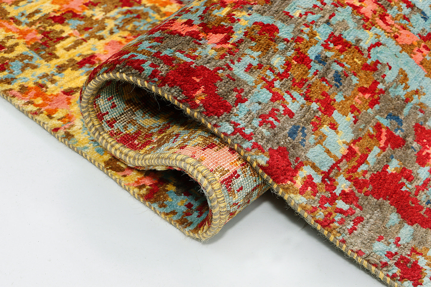 A close-up highlighting the intricate blending of vibrant red, yellow, and blue yarns, where the subtle sheen of hybrid silk contrasts against an earthy, undyed brown wool foundation to reveal faded floral motifs.