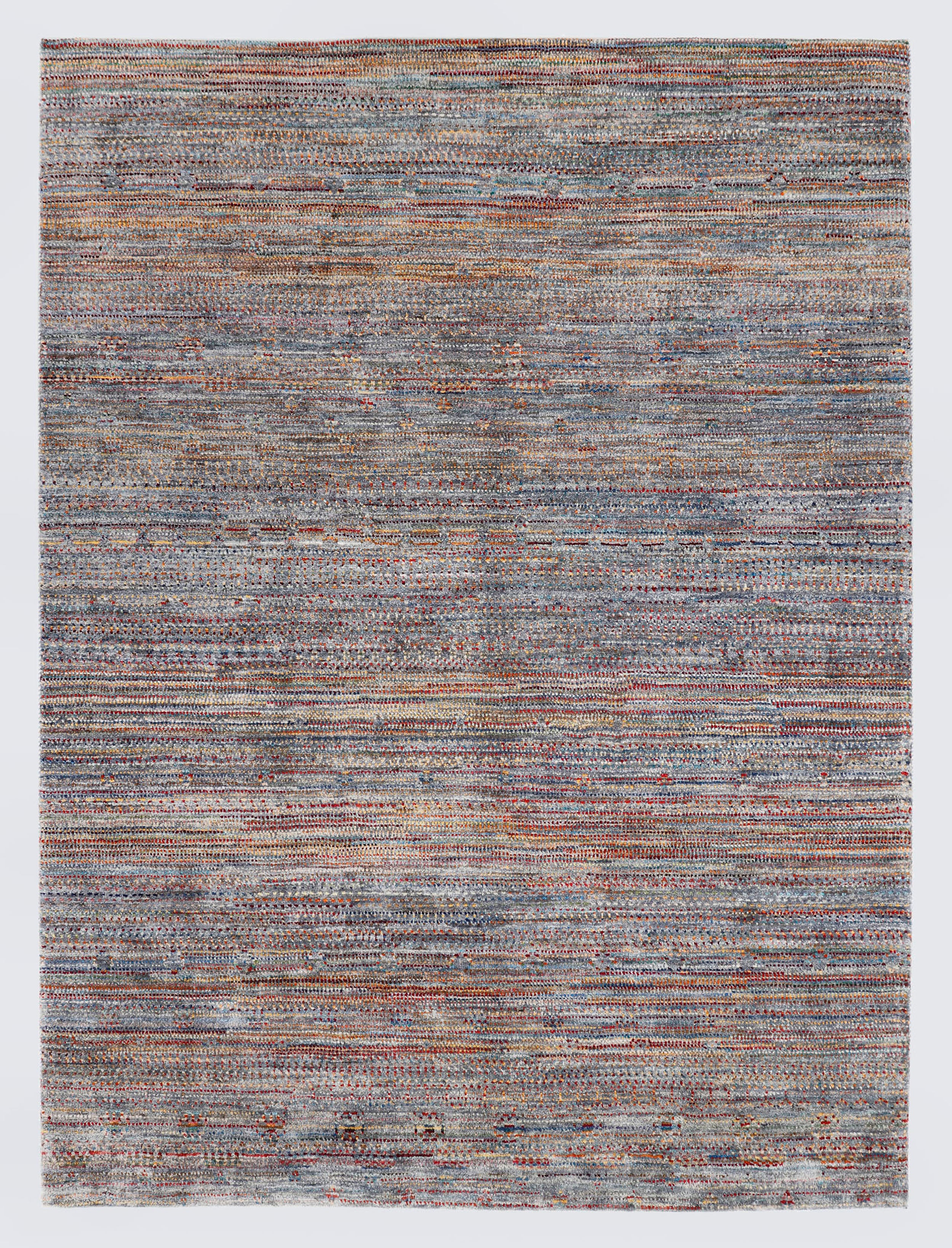 A full architectural view of a high-density hand-knotted Aatish Gabbeh rug featuring a textured silver-grey foundation with a rhythmic scattering of multi-colored nomadic motifs.