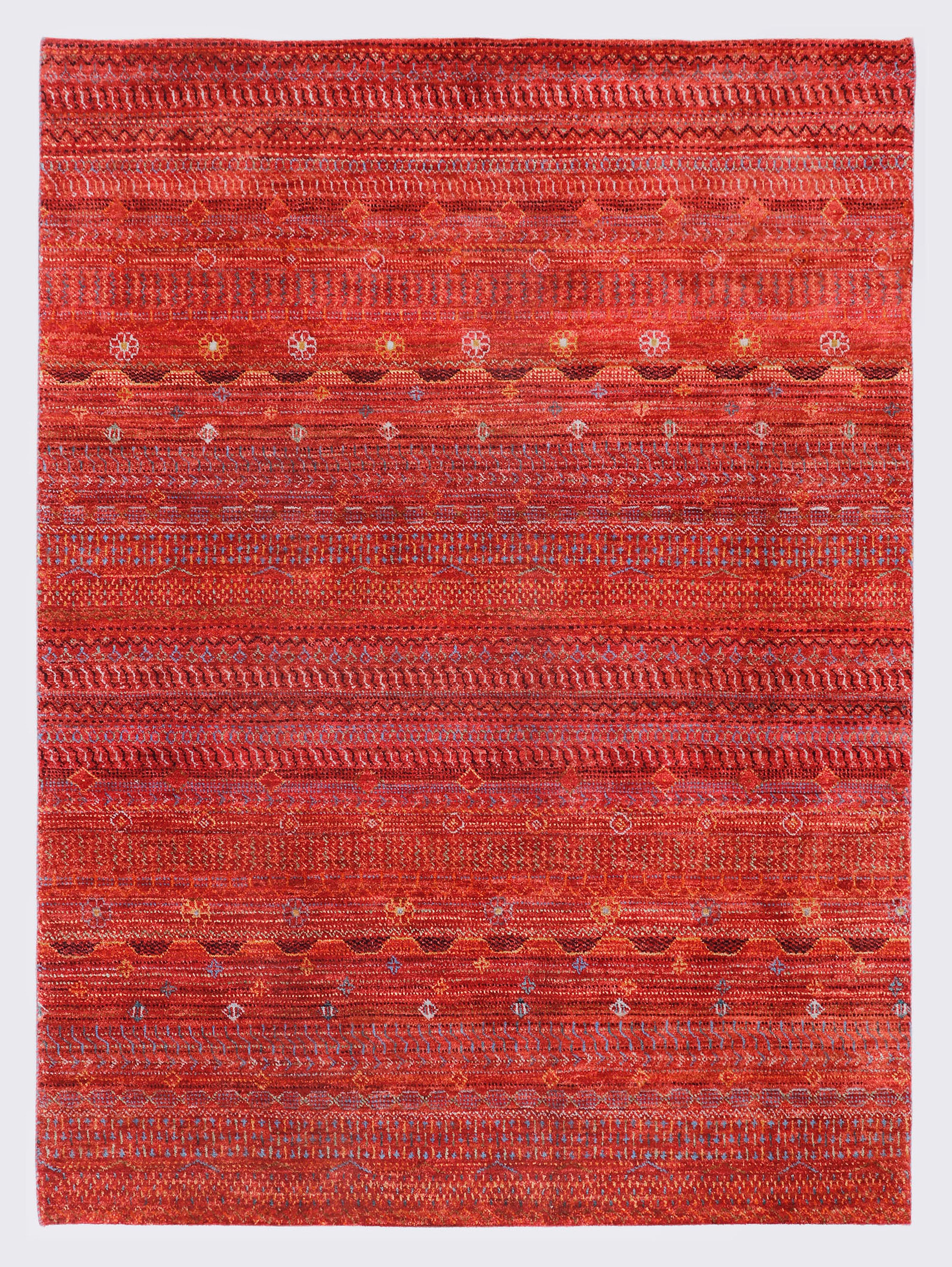 A full view of a vibrant hand-knotted Aatish Gabbeh rug featuring rhythmic horizontal bands of tribal motifs over a saturated red foundation.