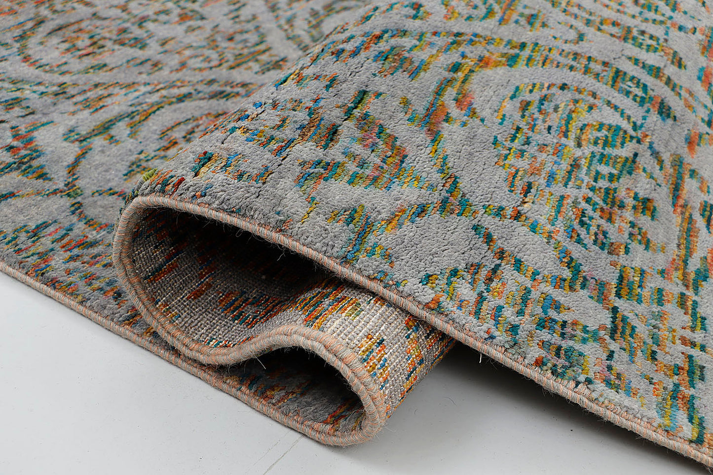 A close-up of a crisp, medium-pile hand-knotted wool rug highlighting the complex artisan technique of using shifting, multi-colored tie-dyed yarns to form traditional repeating motifs.