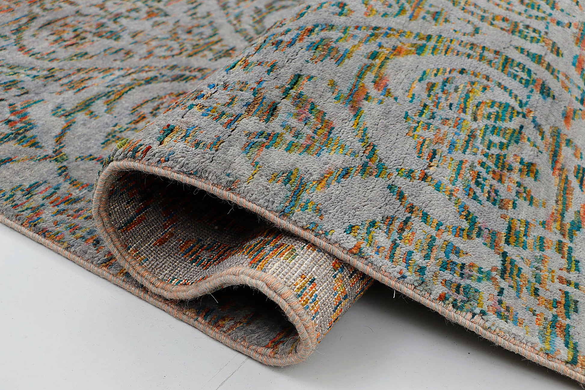 A close-up of a crisp, medium-pile hand-knotted wool rug highlighting the complex artisan technique of using shifting, multi-colored tie-dyed yarns to form traditional repeating motifs.